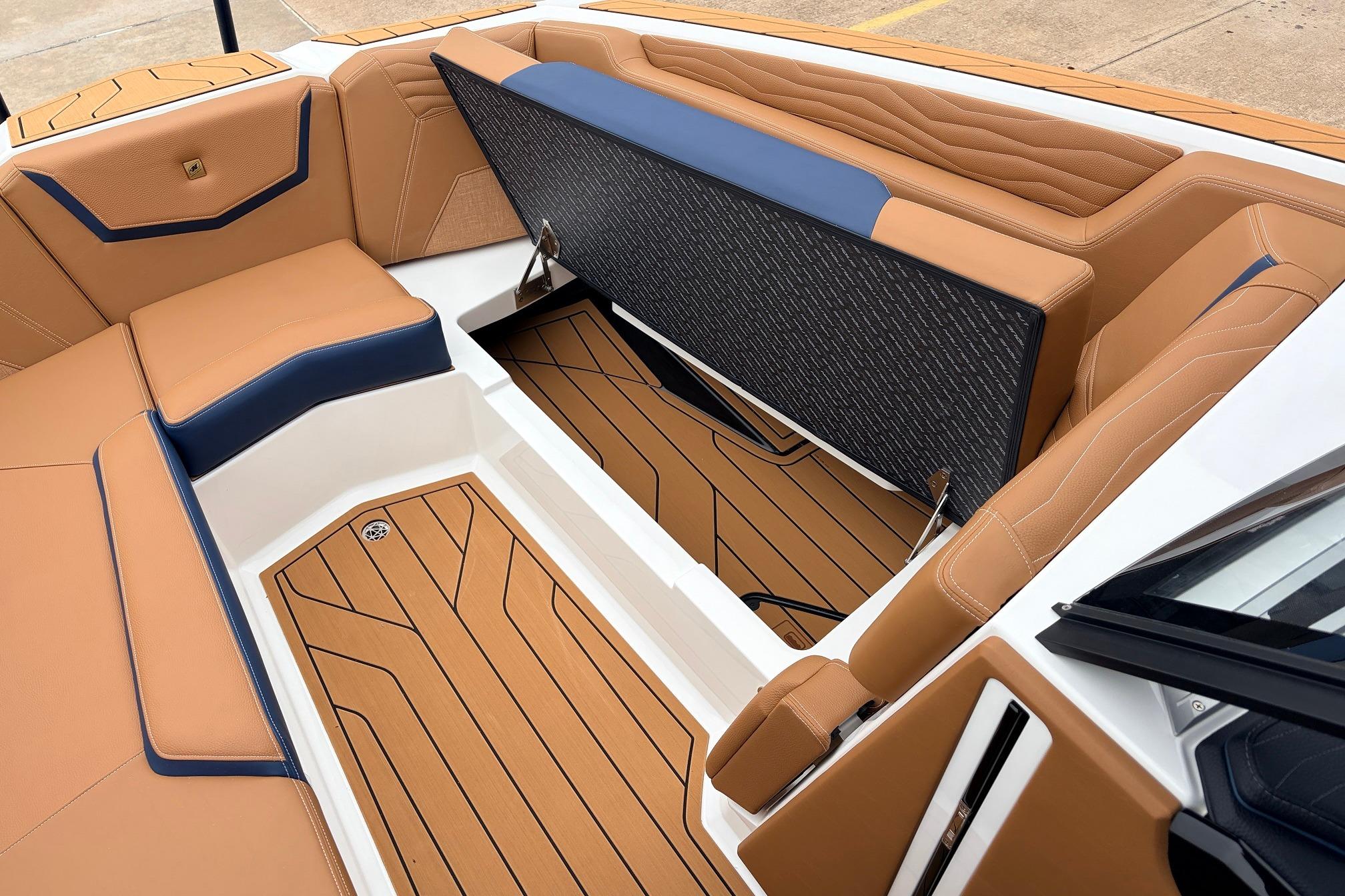 2026 Nautique Super Air Nautique G25 interior with tan and blue seating, open storage compartment.