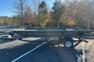 2025 Tracker Grizzly 1860 Utility boat on trailer in parking lot, surrounded by autumn trees.
