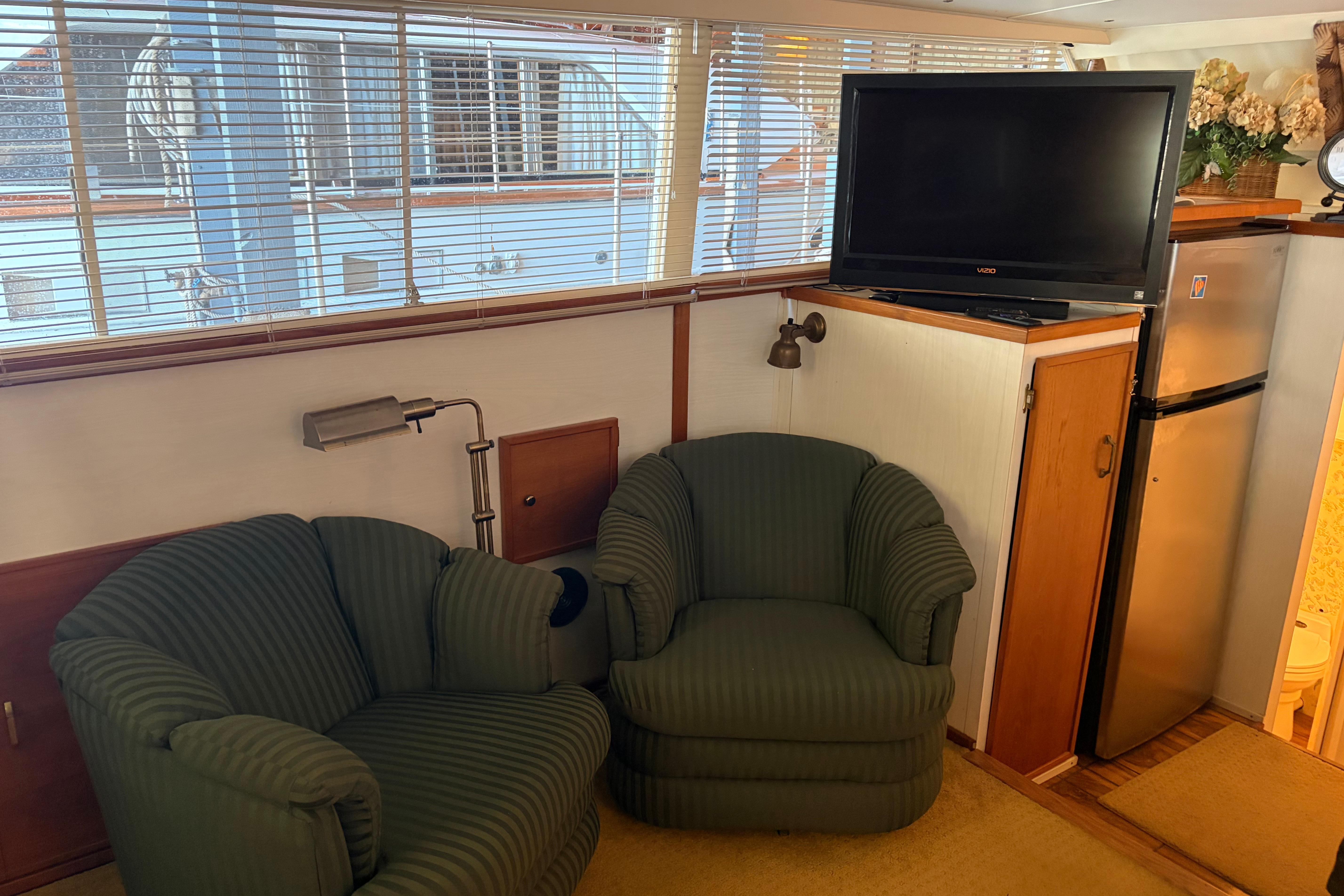 Interior of 1971 Chris-Craft 42 Commander with green chairs, TV, and mini fridge.