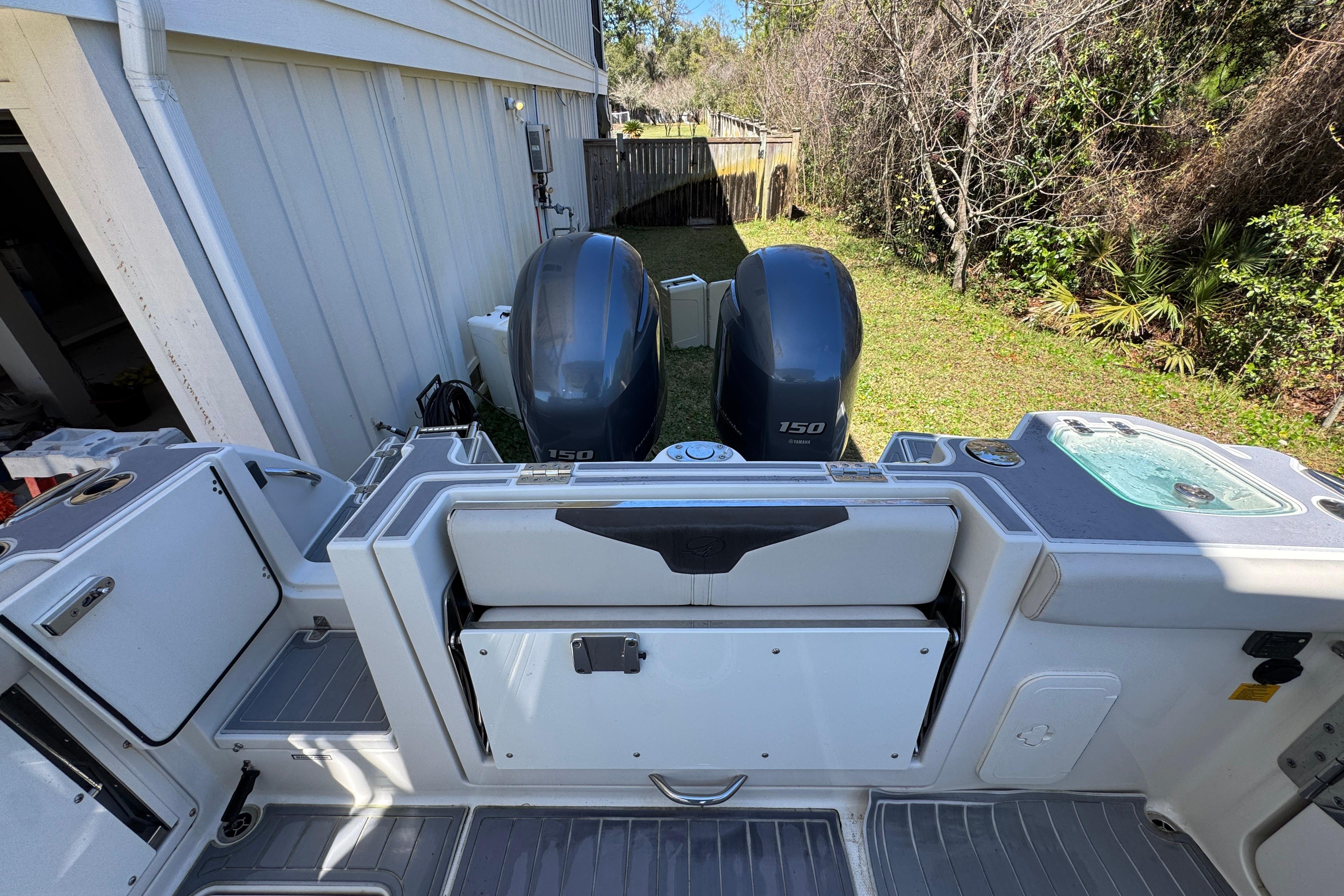 2022 Sailfish 276 DC boat with dual 150 horsepower engines, docked near a house.