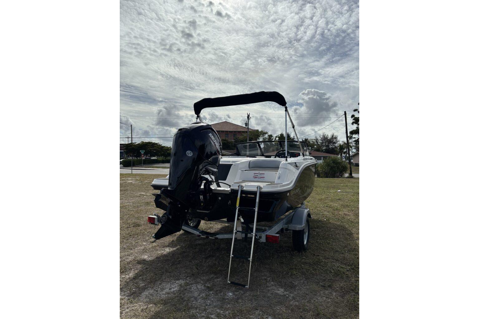 2025 Bayliner Element M17 boat on trailer, parked outdoors under cloudy sky.