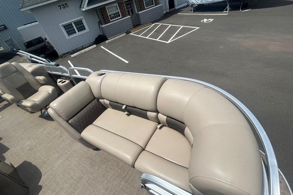 2023 Sun Tracker Party Barge 22 DLX with beige seating in a parking lot.