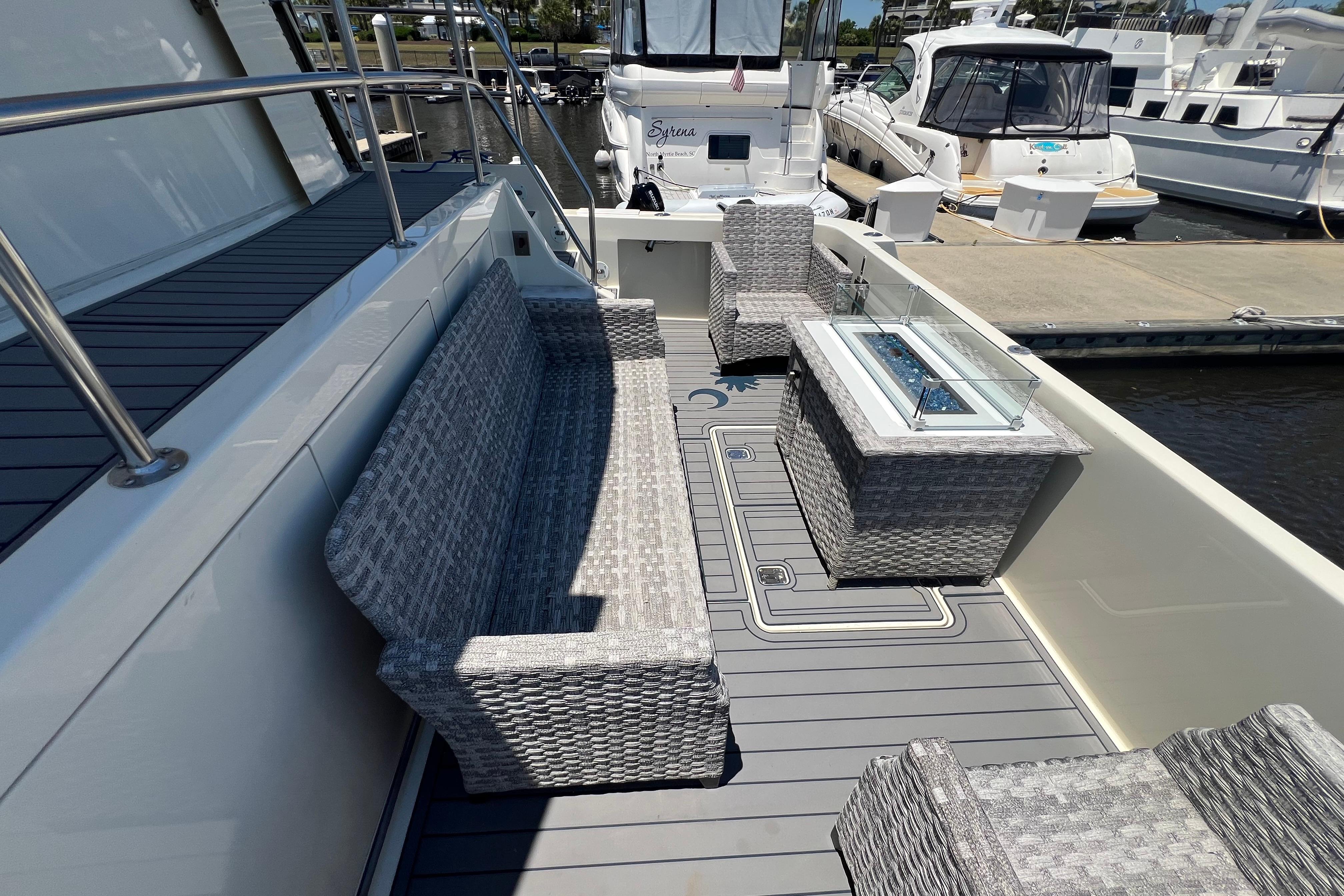 Outdoor seating area on 1987 Hatteras 70 Cockpit Motor Yacht with wicker furniture and fire table.