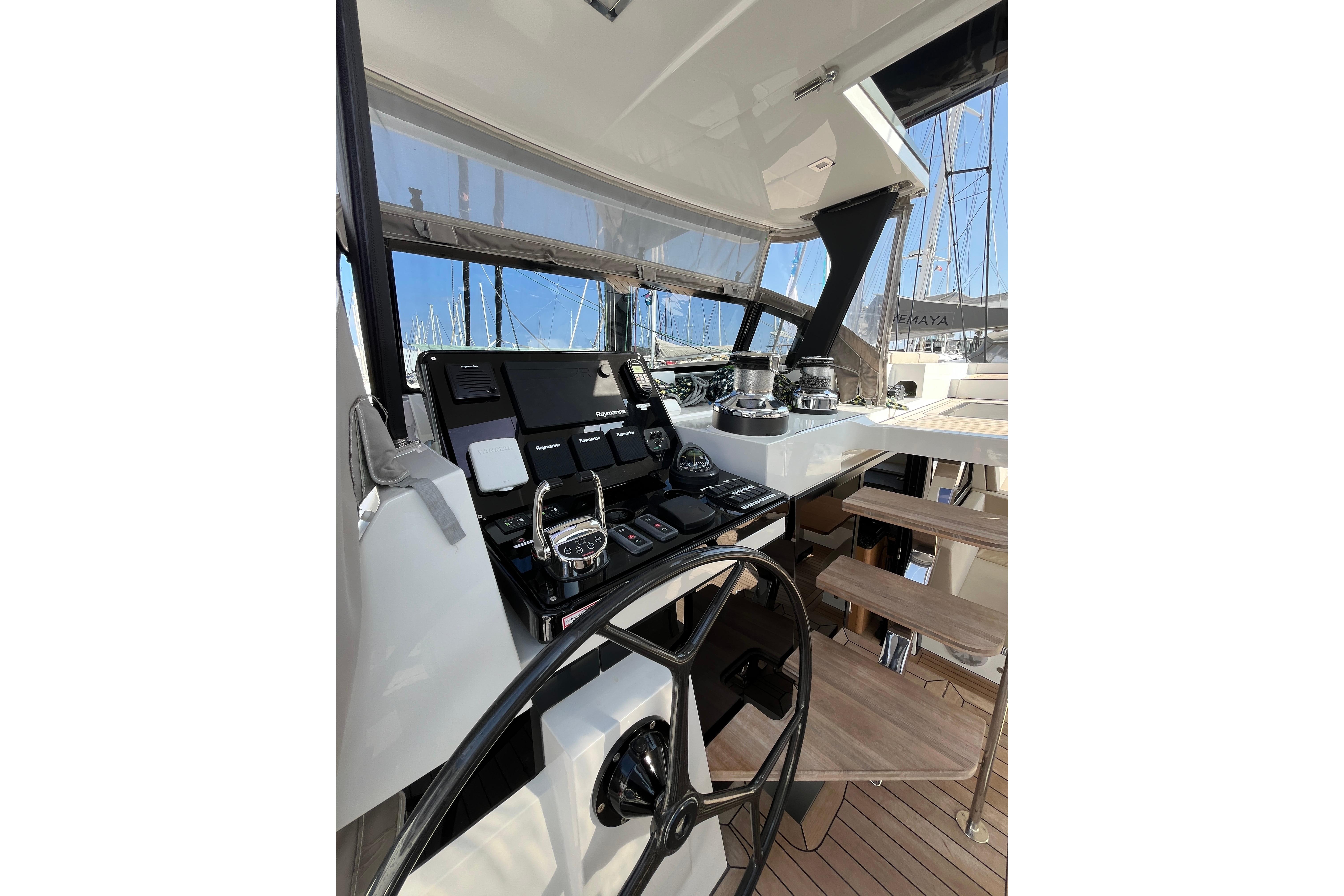 Helm station of 2021 Privilege 580 SIGNATURE yacht with modern controls and wooden steps.