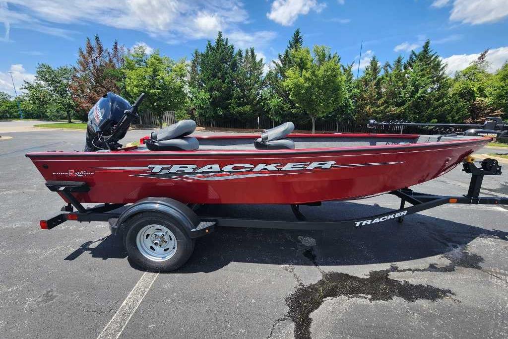 2025 Tracker Super Guide V-16 T boat, red, parked on trailer, sunny day.