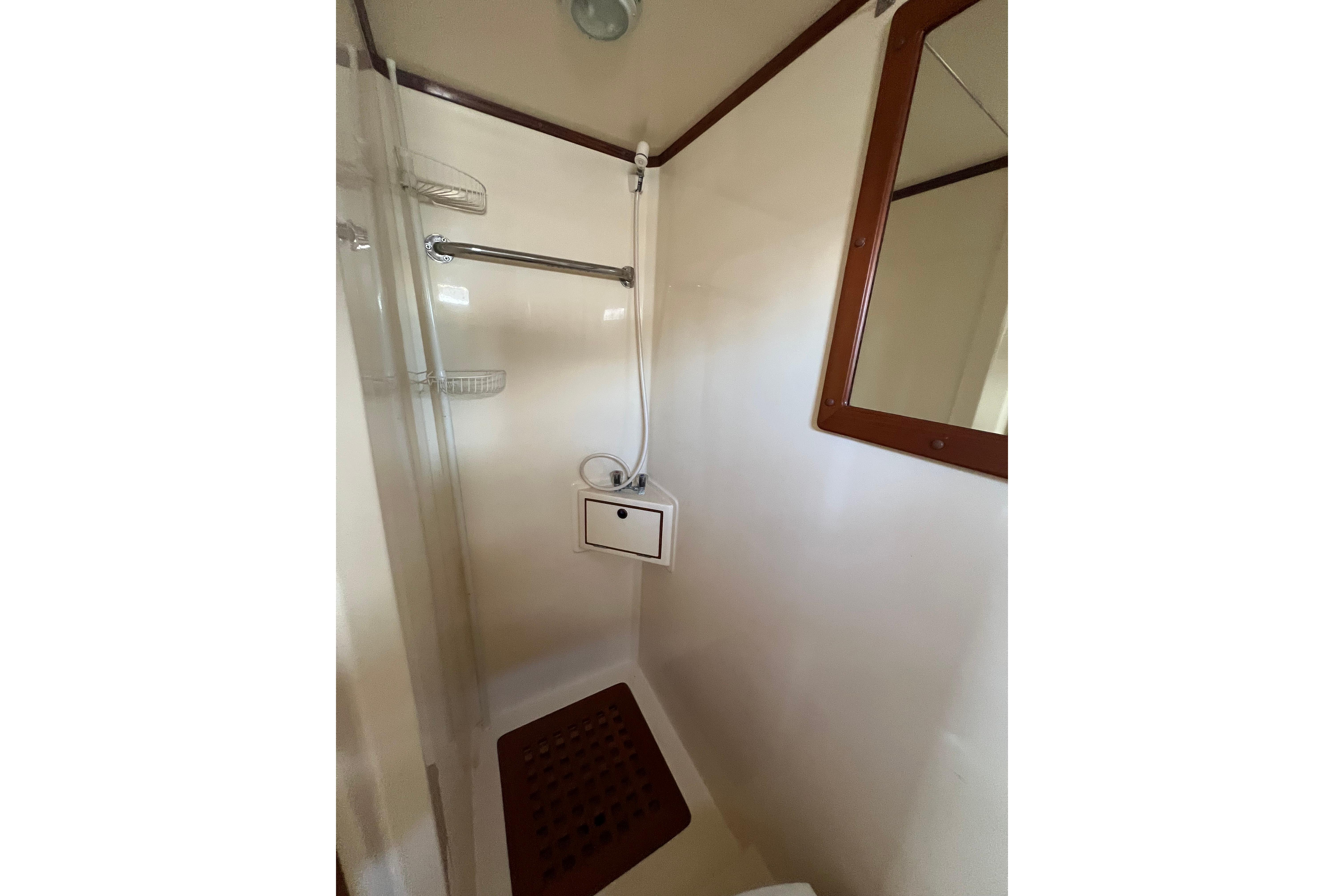 Shower area in 2007 Heritage East 36 Sundeck Trawler, featuring a mirror and wooden floor mat.