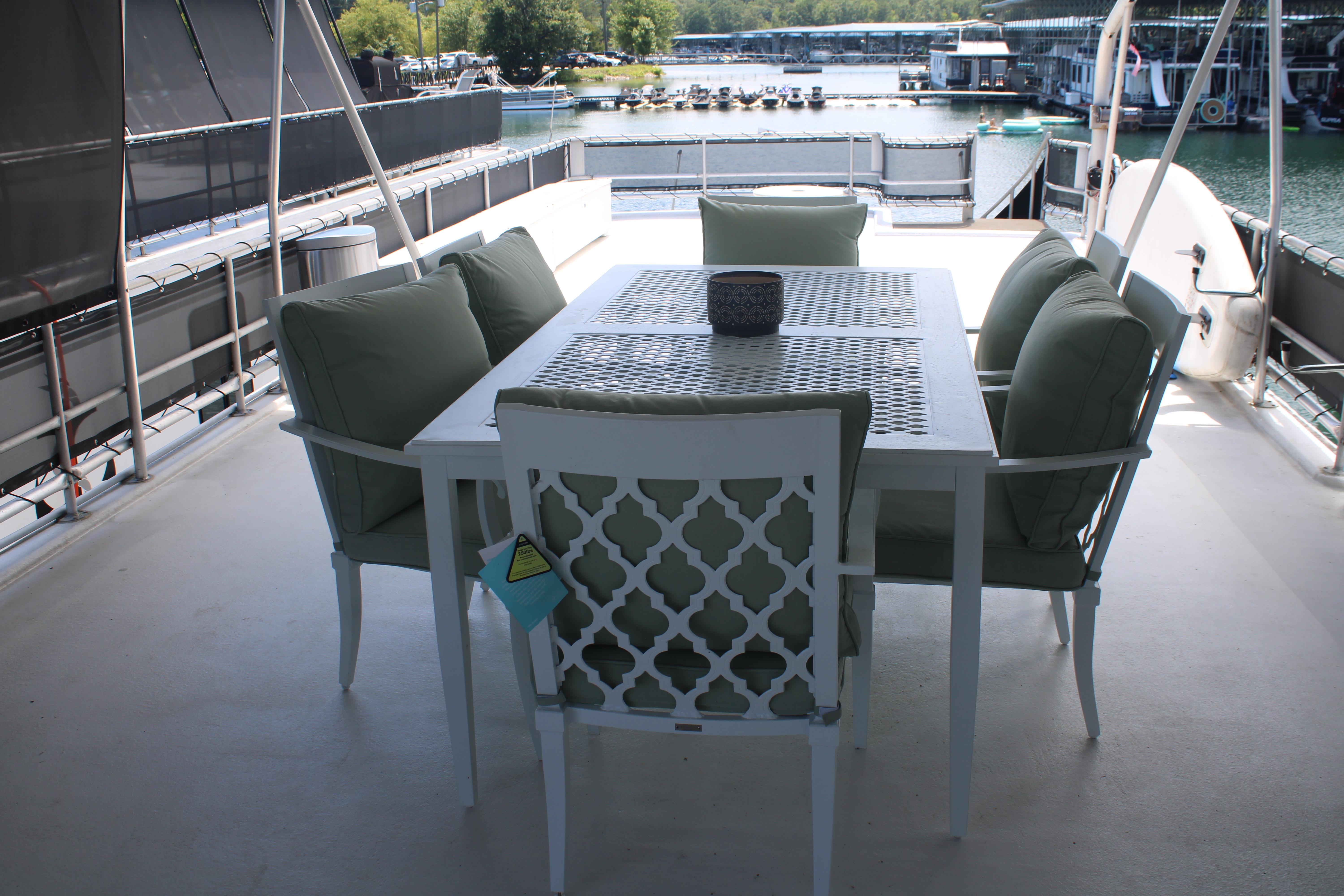 Outdoor dining area on 1992 Sumerset 66 houseboat, featuring cushioned chairs and a waterfront view.