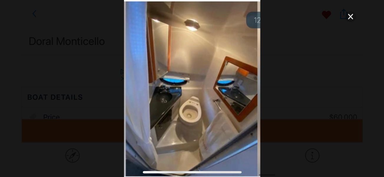 Interior view of a boat cabin with a toilet, sink, and mirror.