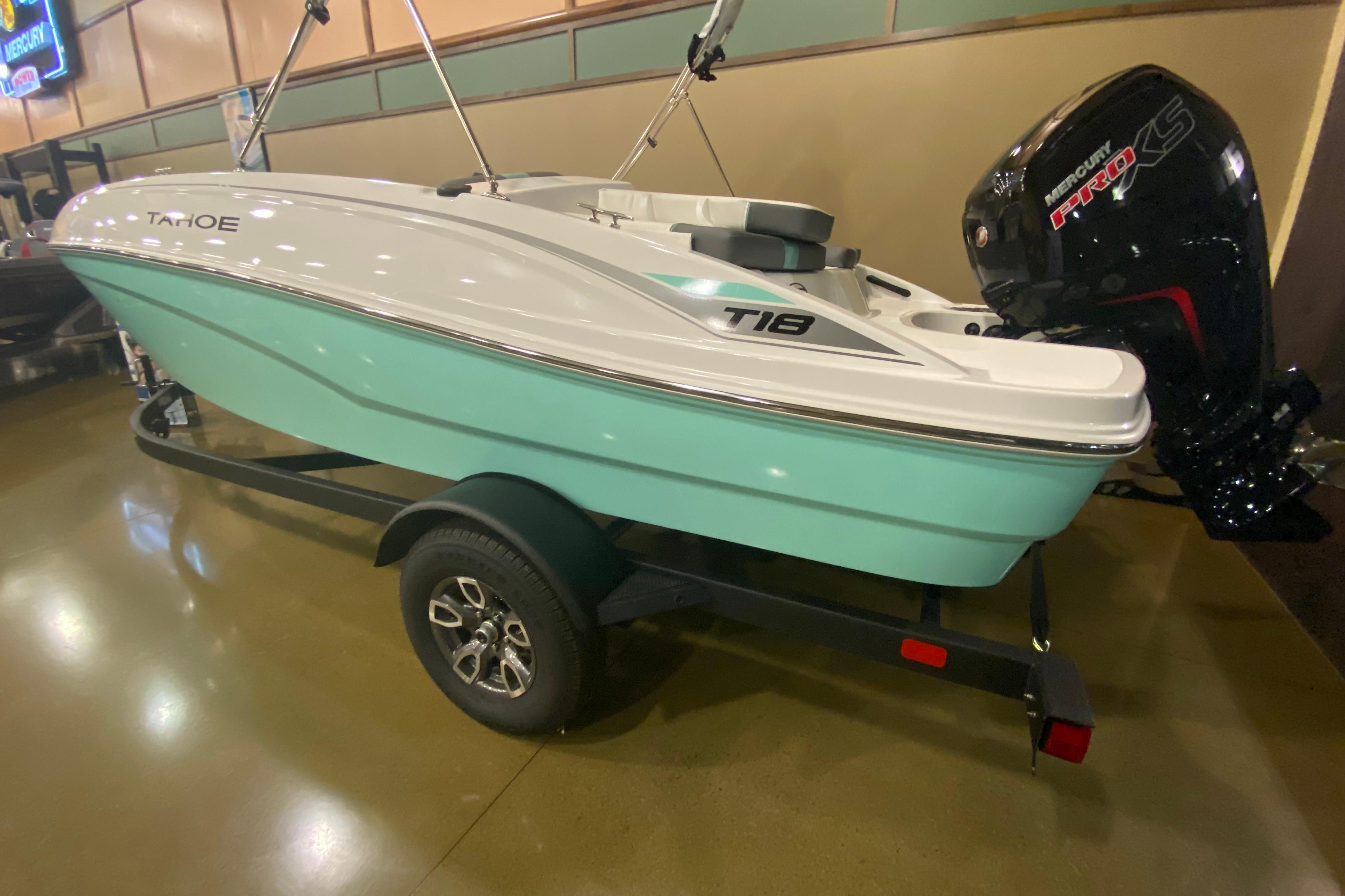 2026 Tahoe T18 boat with outboard motor on a trailer in showroom.