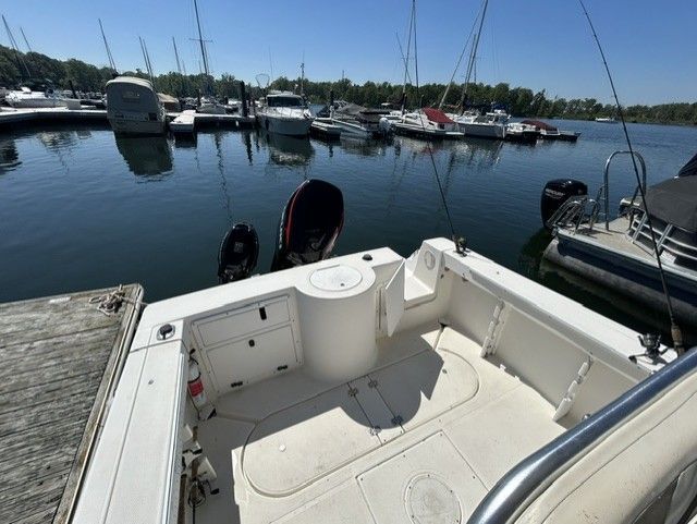 The image shows the stern of a 2000 Aquasport Osprey 250 boat in a marina.