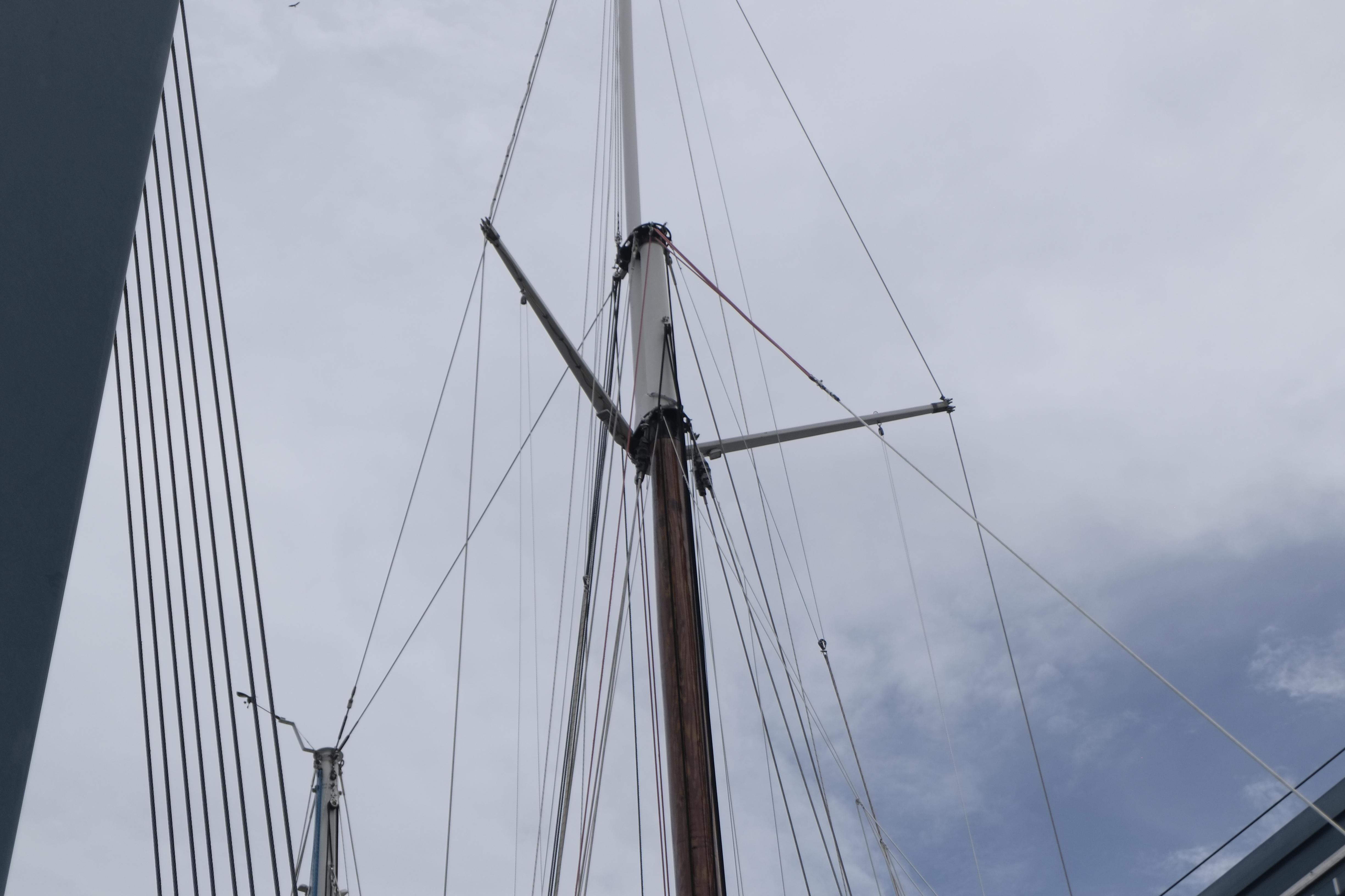 Tall mast of a 2006 Custom Bud Macintosh schooner against a cloudy sky.