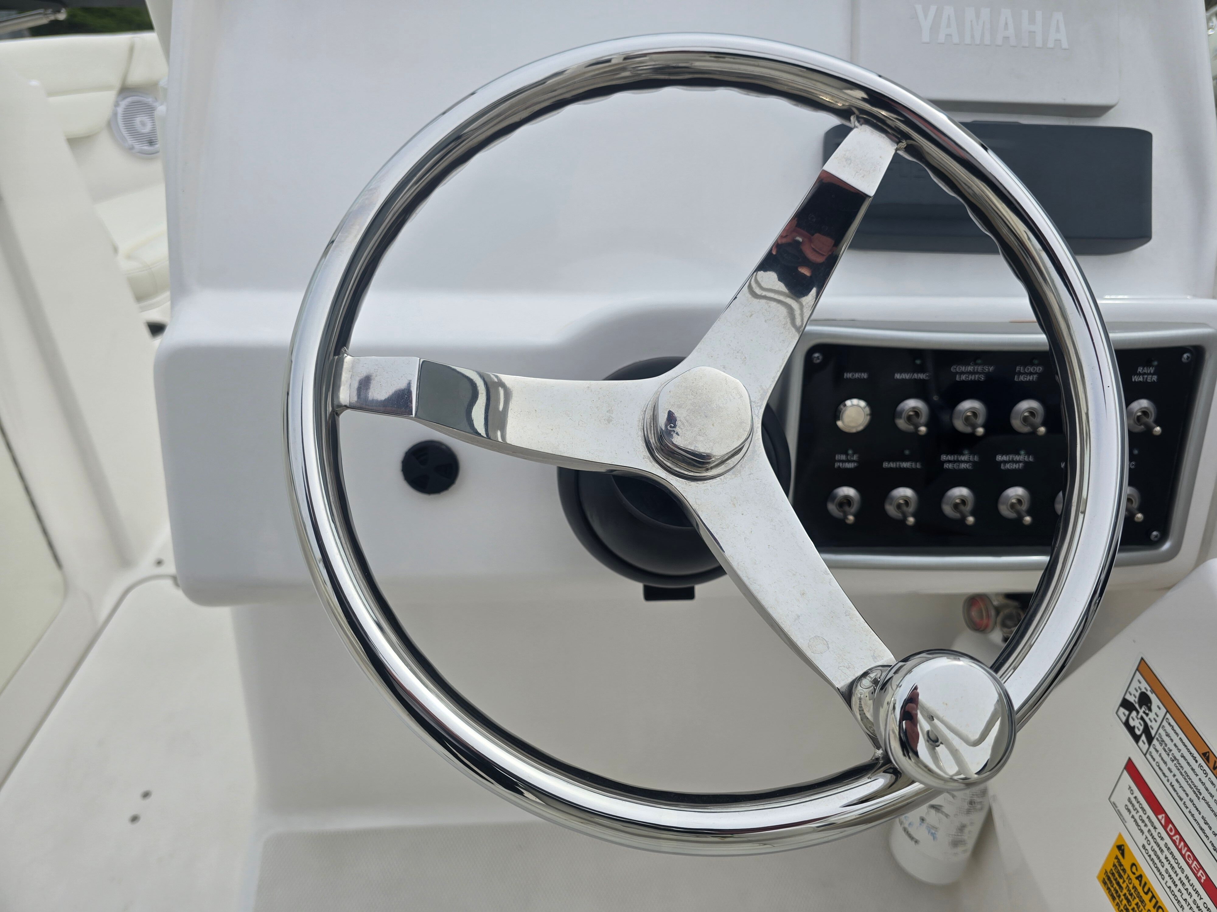 Steering wheel and dashboard of a boat with Yamaha logo and switches.