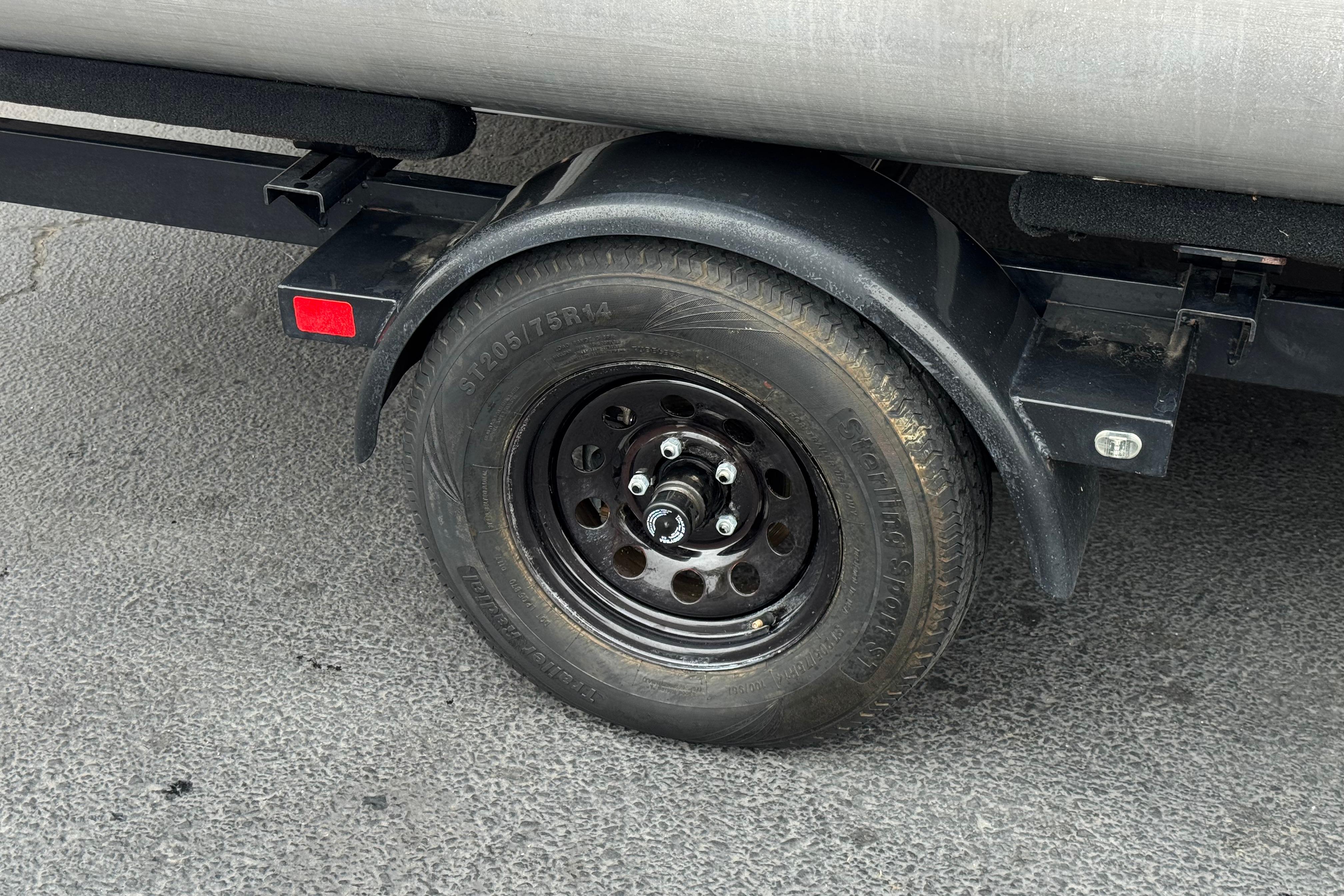 Trailer wheel of 2020 Manitou 18 Aurora LE on asphalt surface.