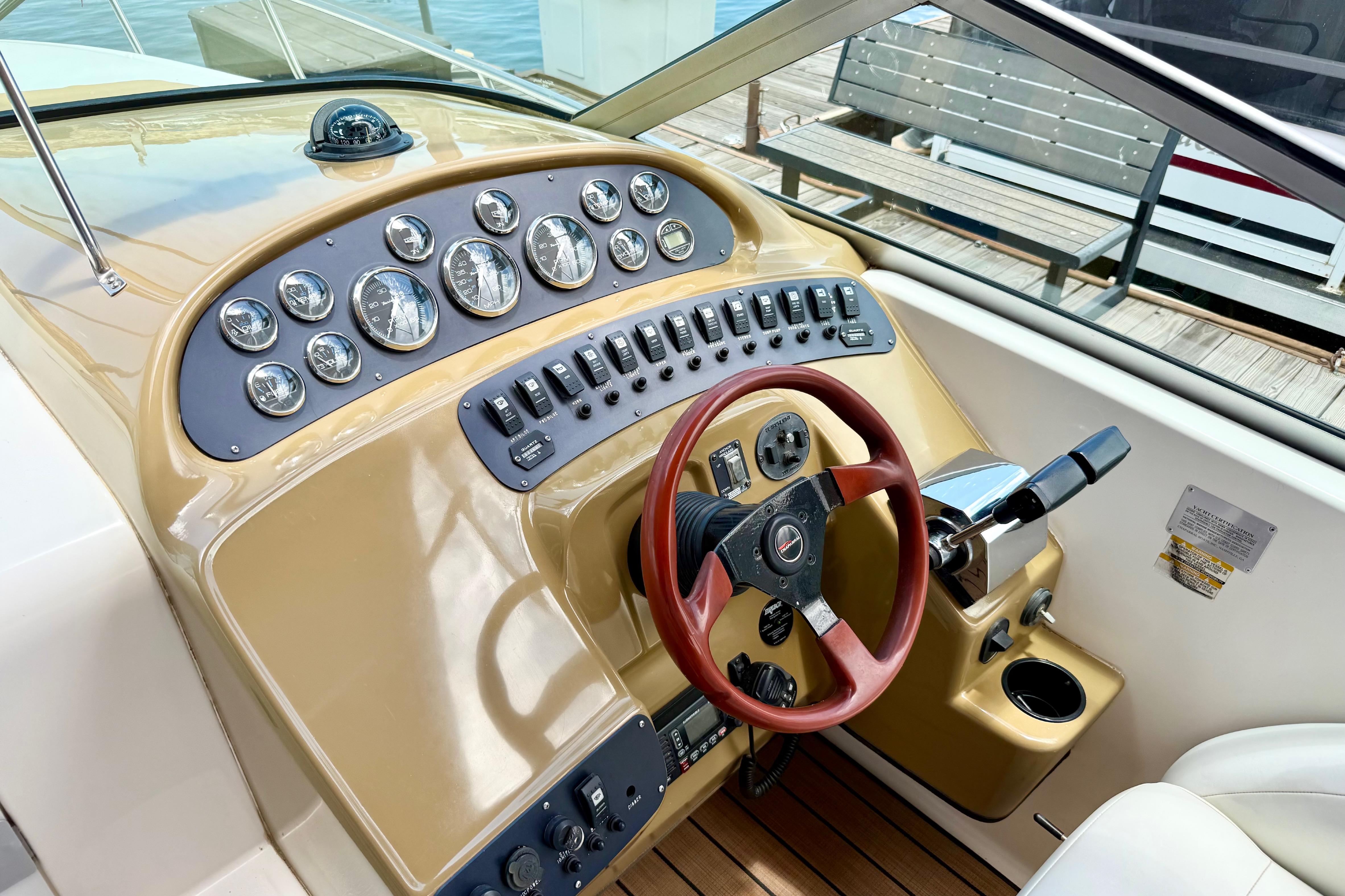1999 Chaparral Signature 300 boat dashboard with gauges, switches, and wooden steering wheel.
