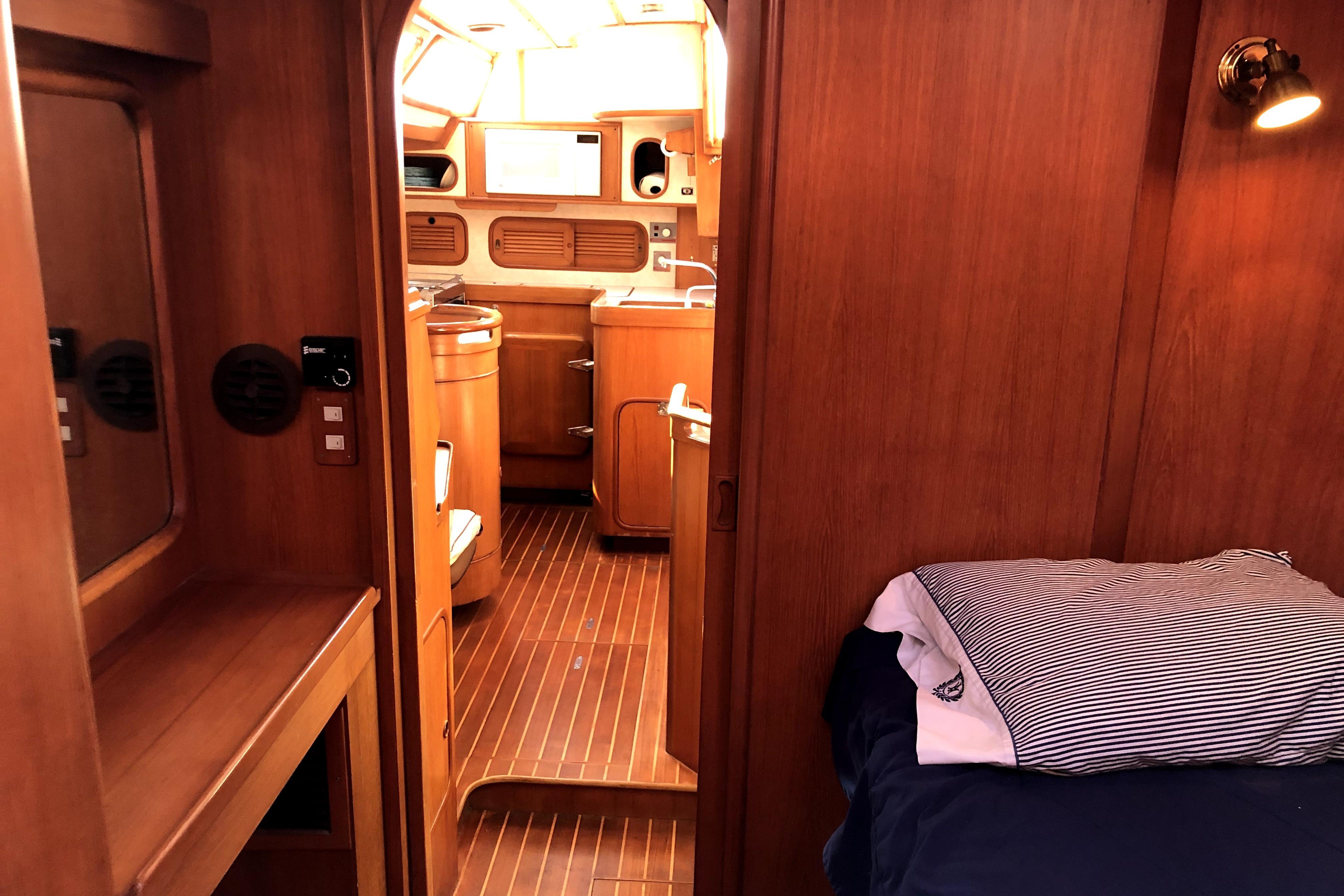 Interior of 1989 Taswell 43 yacht, featuring wooden cabinetry and cozy sleeping area.