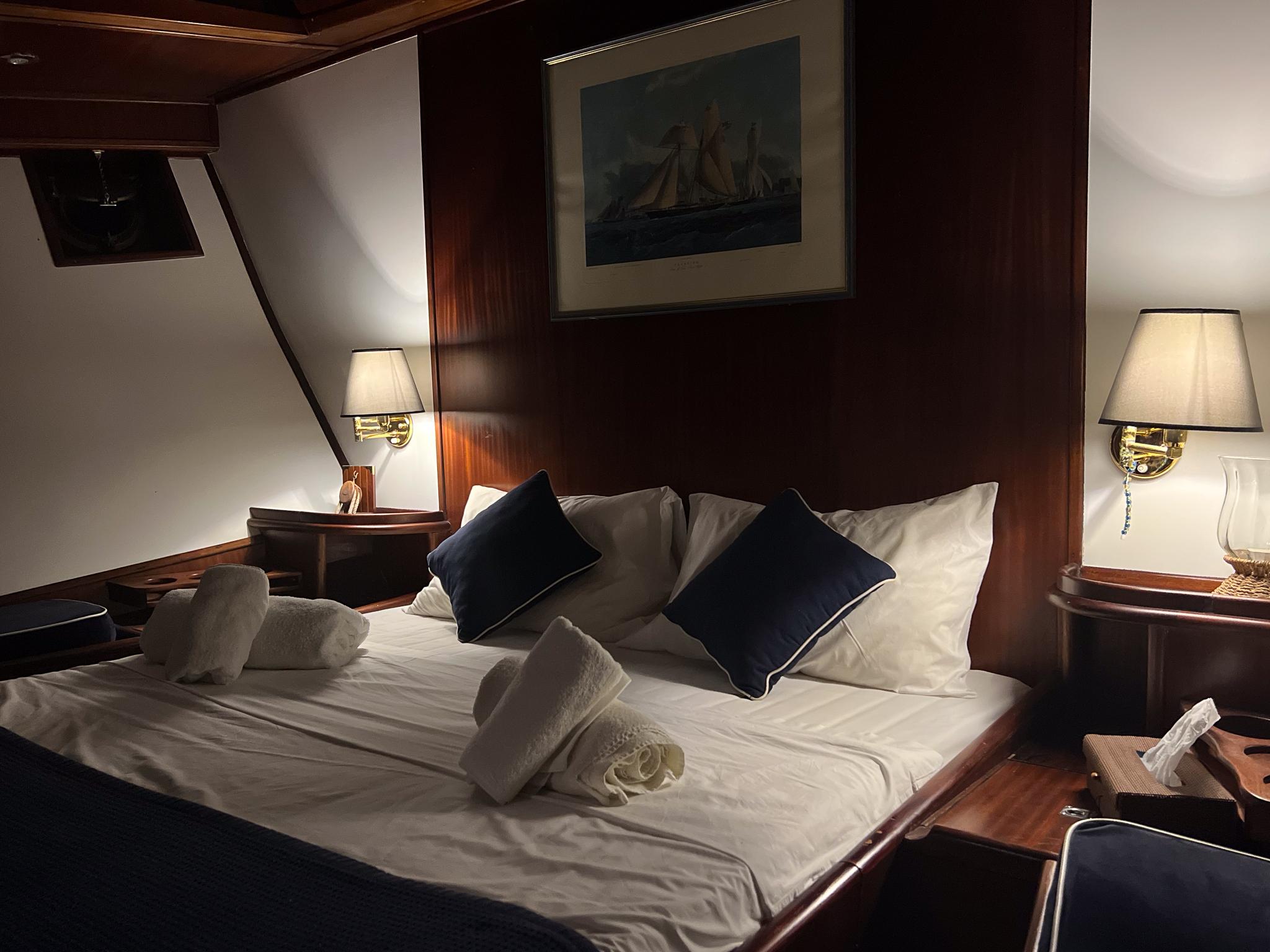 Luxurious cabin interior on a 1969 Psarros Shipyard yacht, featuring elegant bedding and warm lighting.