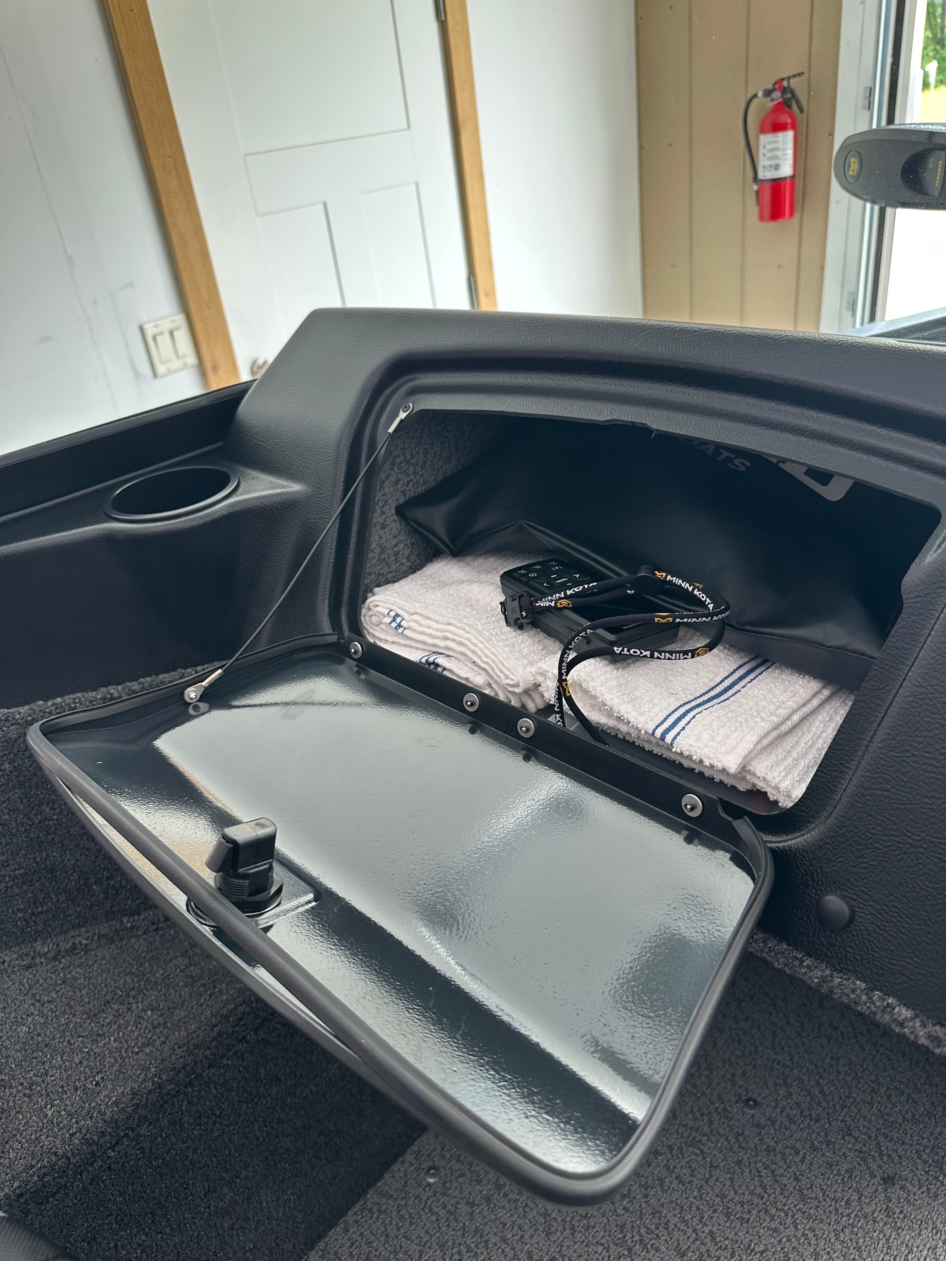 The image shows the open glove compartment of a Lund Pro Angler 1650 boat with a towel and a device inside.