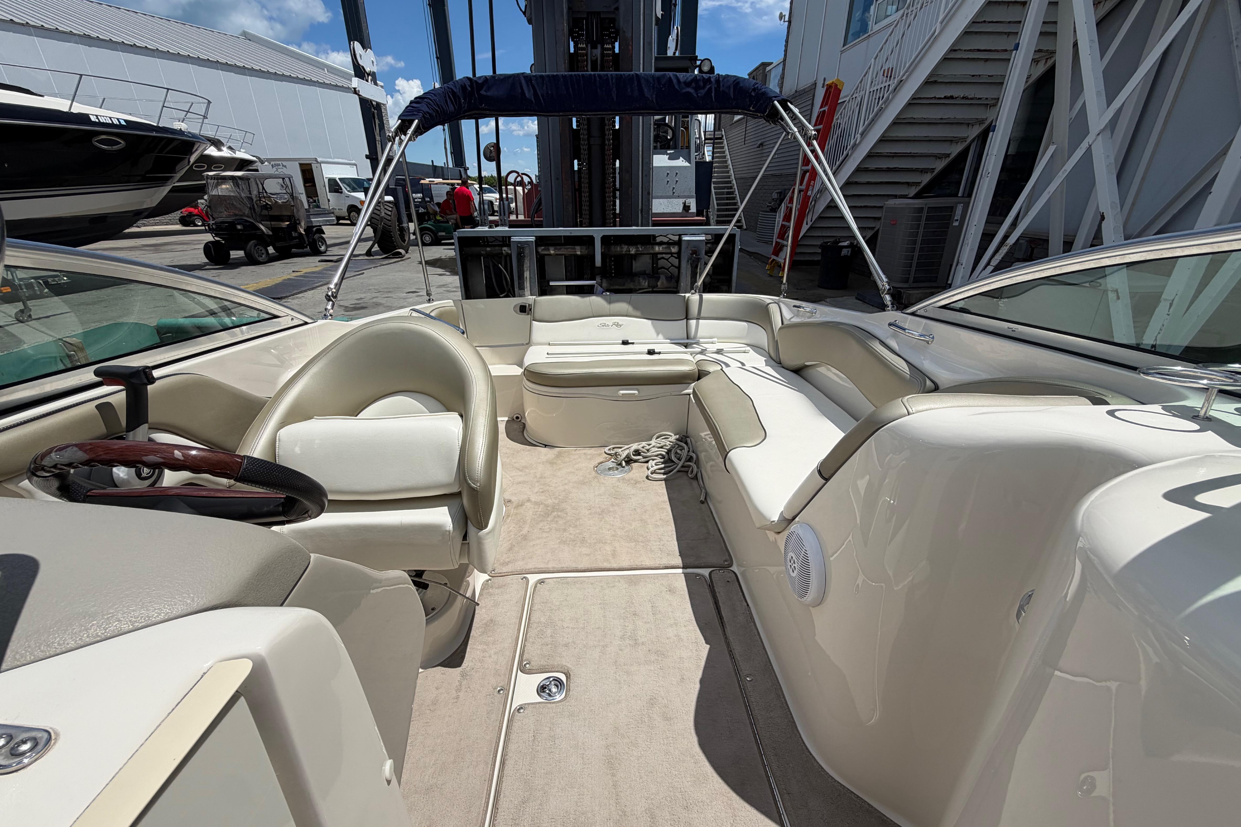 2004 Sea Ray 240 Sundeck interior with seating, steering wheel, and open deck area.