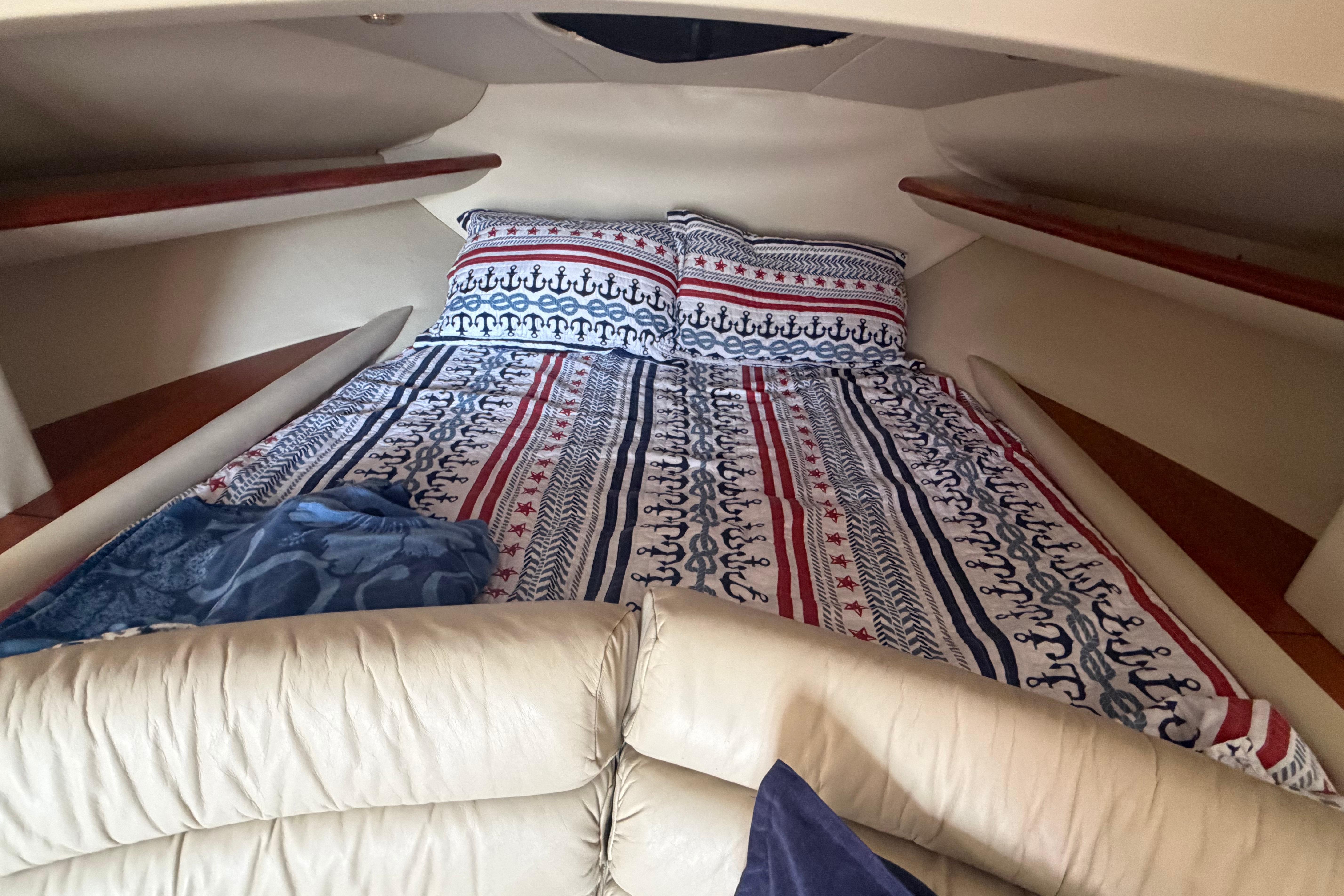 Cozy cabin interior of 2000 Sunseeker Superhawk 34 with nautical-themed bedding.