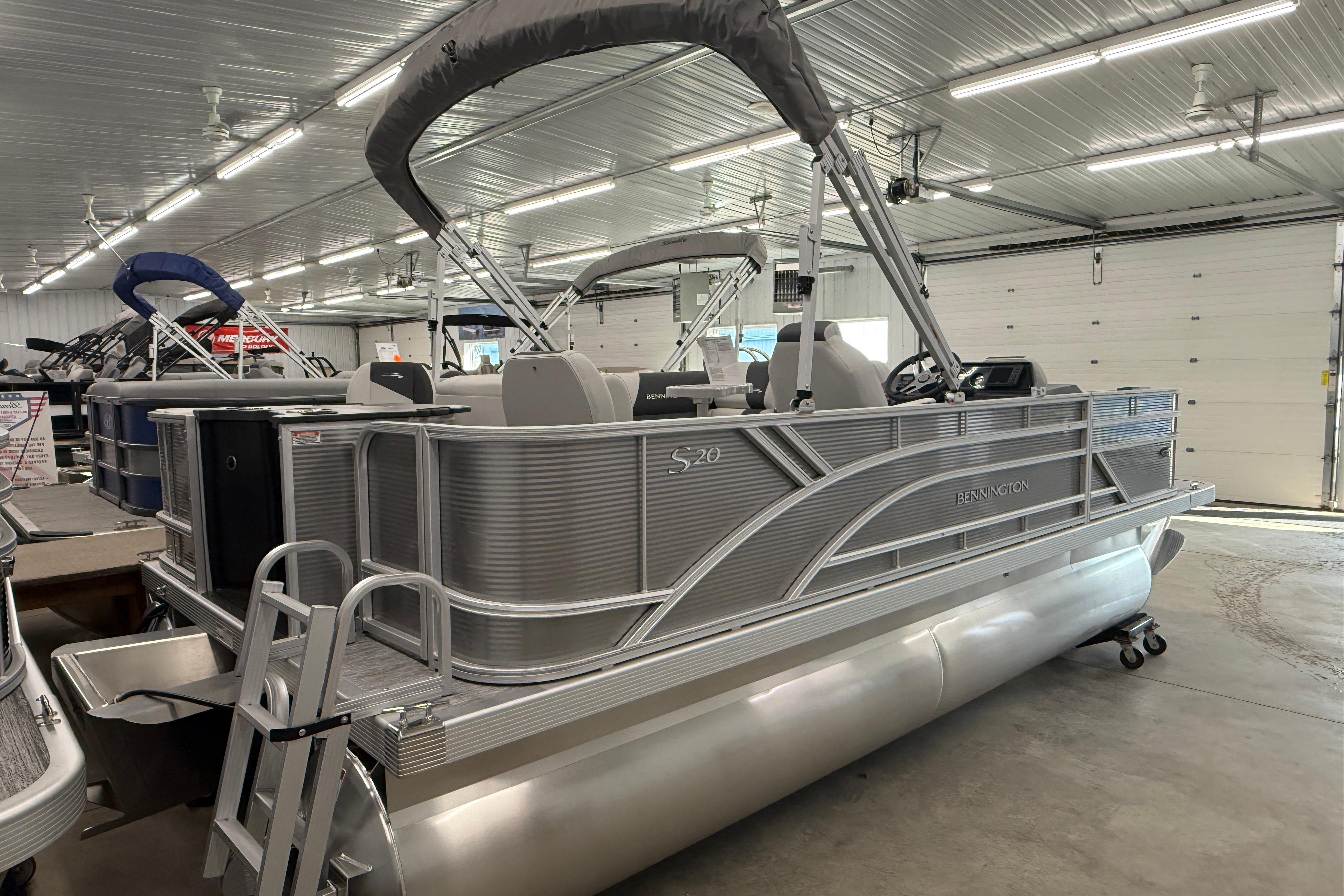 2026 Bennington 20 SF pontoon boat in a showroom, featuring sleek aluminum design.