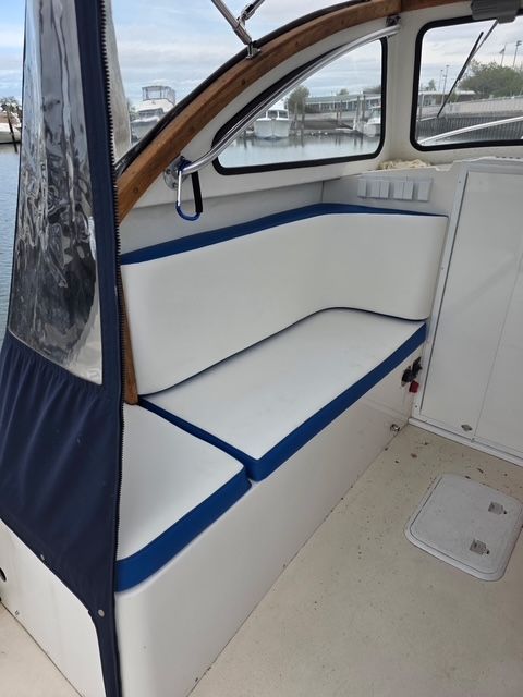 The boat has white seats with blue accents and is docked in a marina.