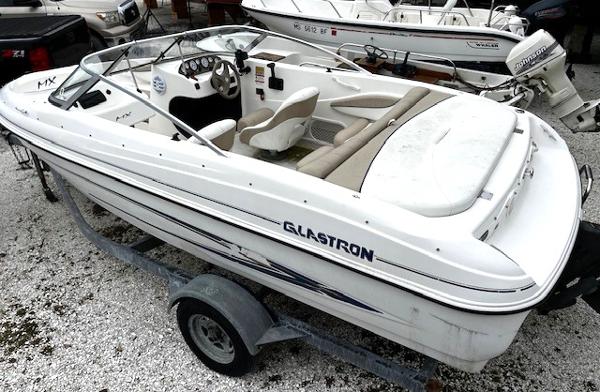 2005 Glastron MX boat on trailer, white exterior, open seating, parked on gravel.