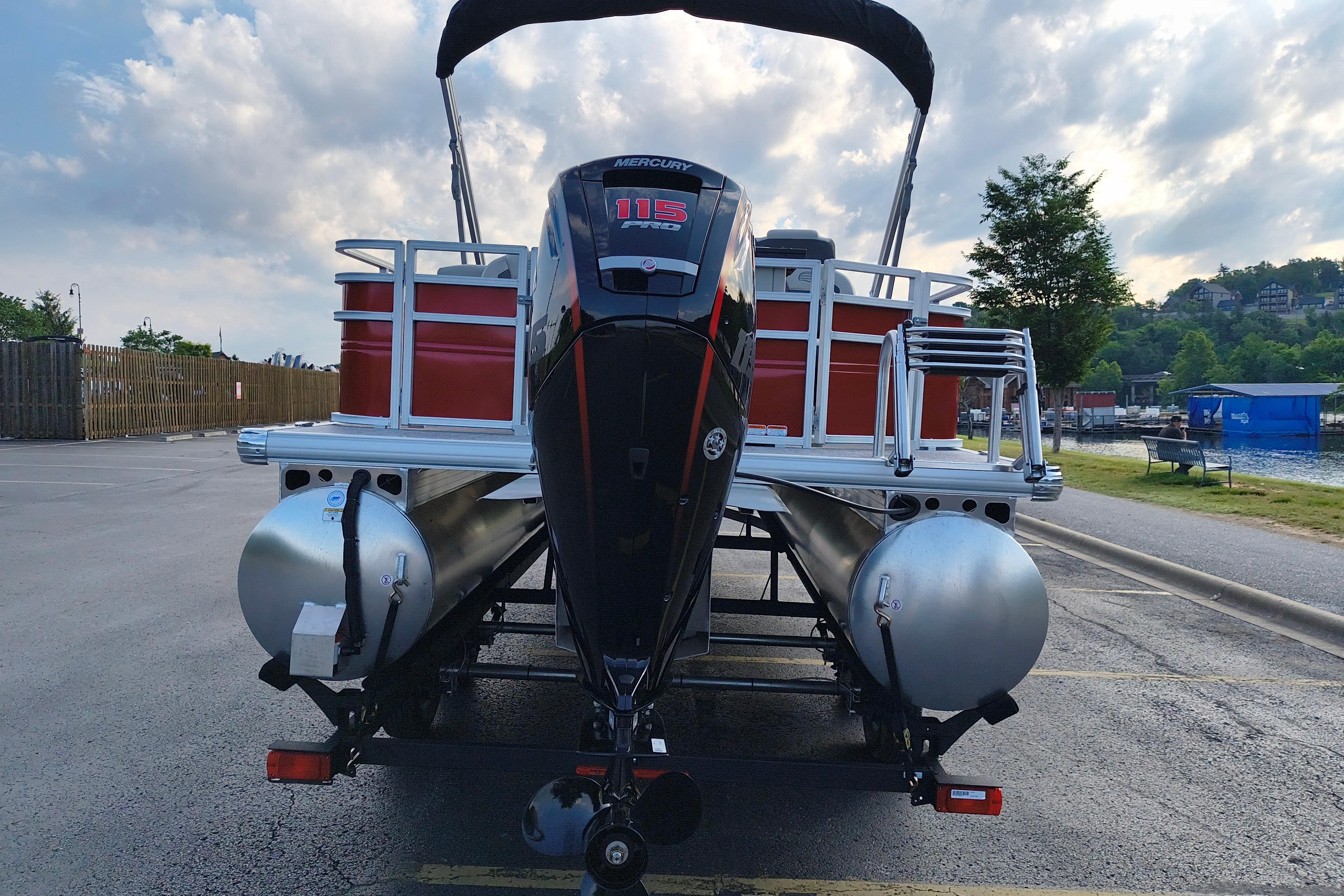 2026 Sun Tracker Fishin' Barge 22 DLX pontoon boat with Mercury 115 engine, docked by a lake.