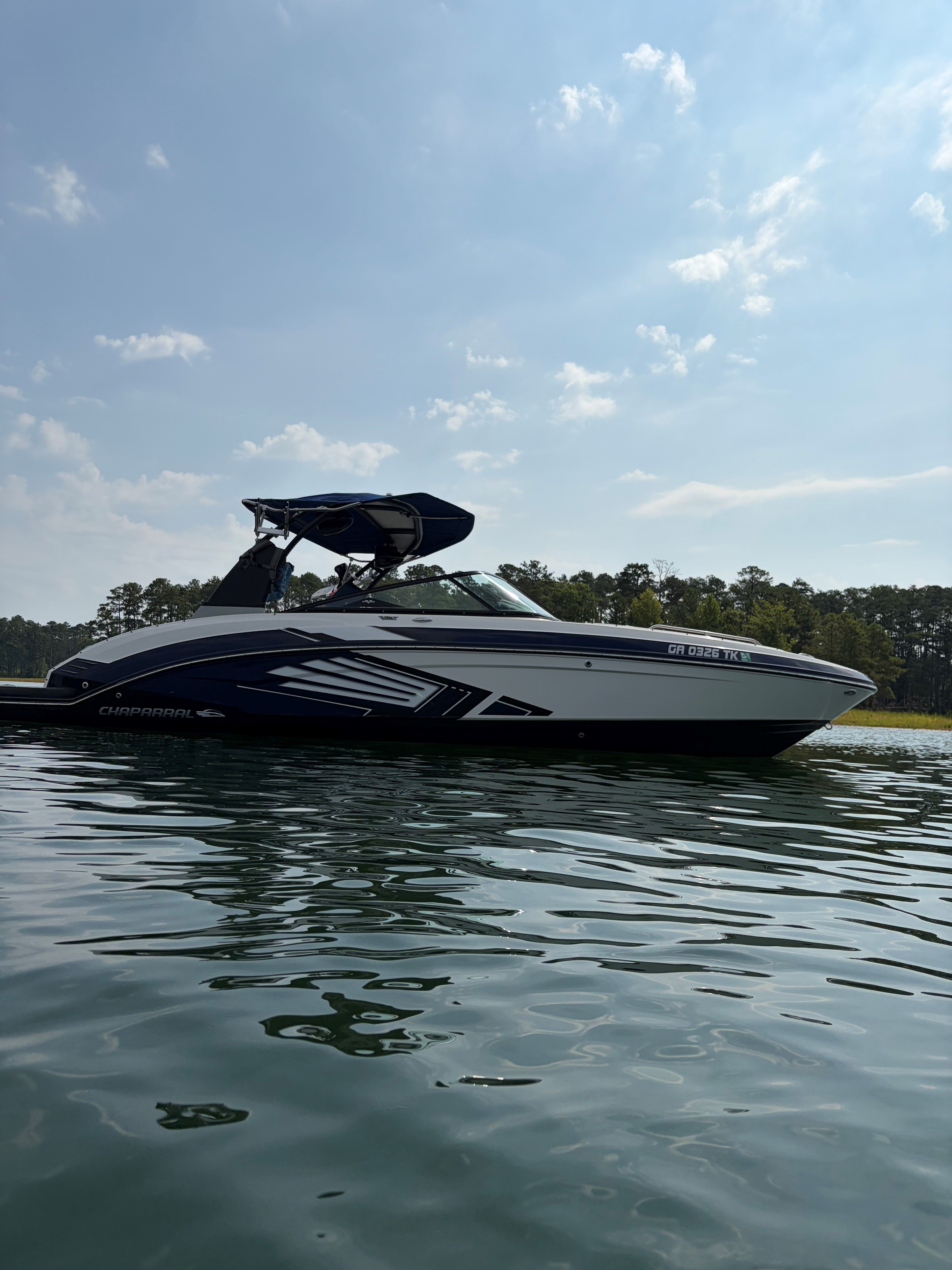 A 2015 Chaparral Vortex 243 VRX on calm water with a blue sky in the background.