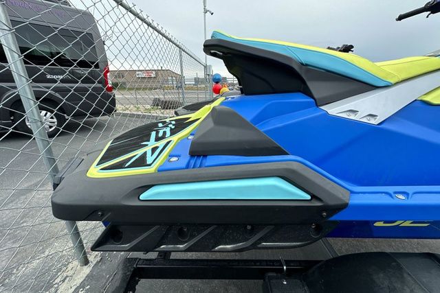 A Yamaha WaveRunner Jetblaster Pro in blue and yellow sits on a trailer next to a fence.