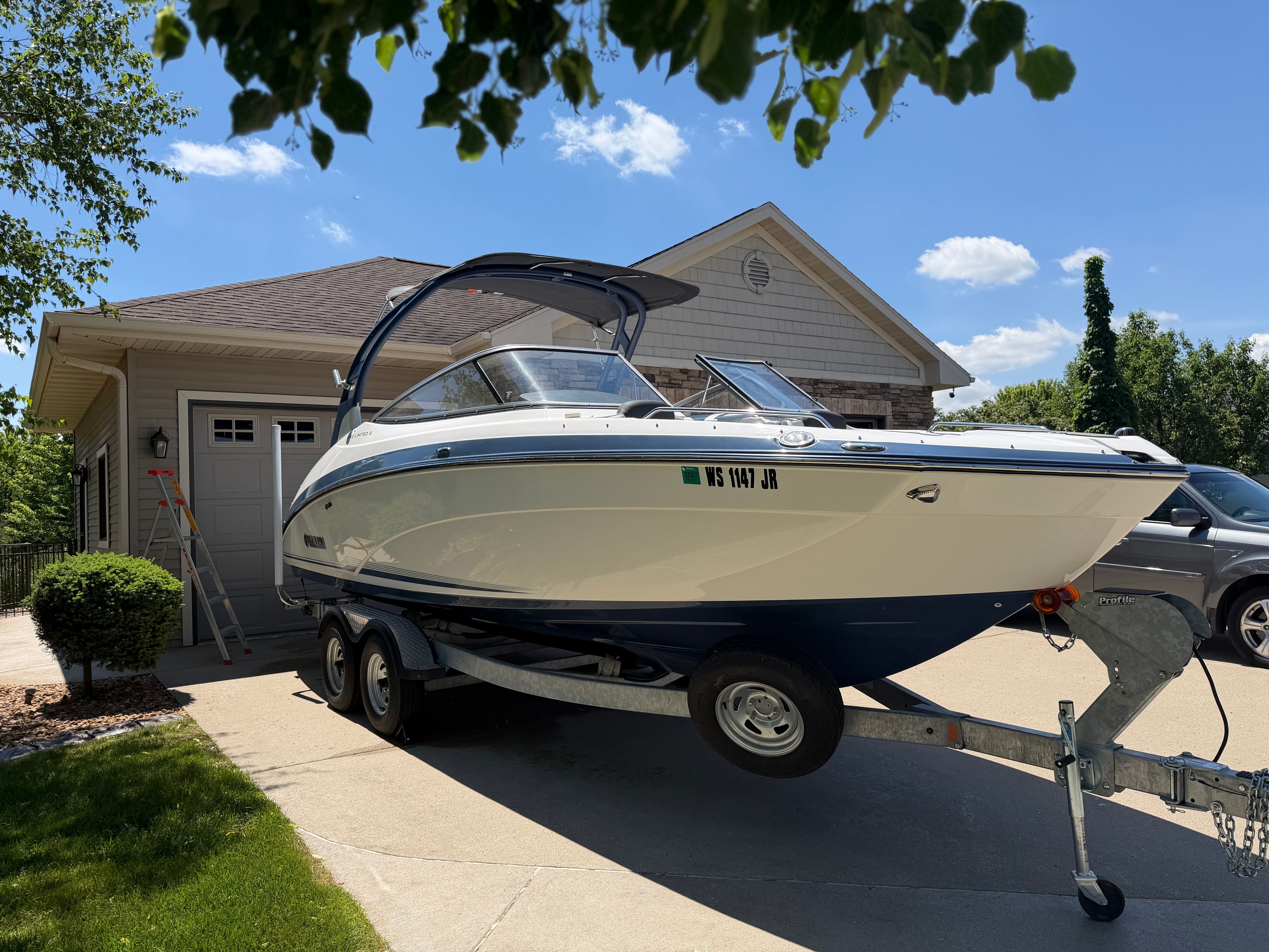 A 2018 Yamaha 242 Limited S boat on a trailer in front of a garage.