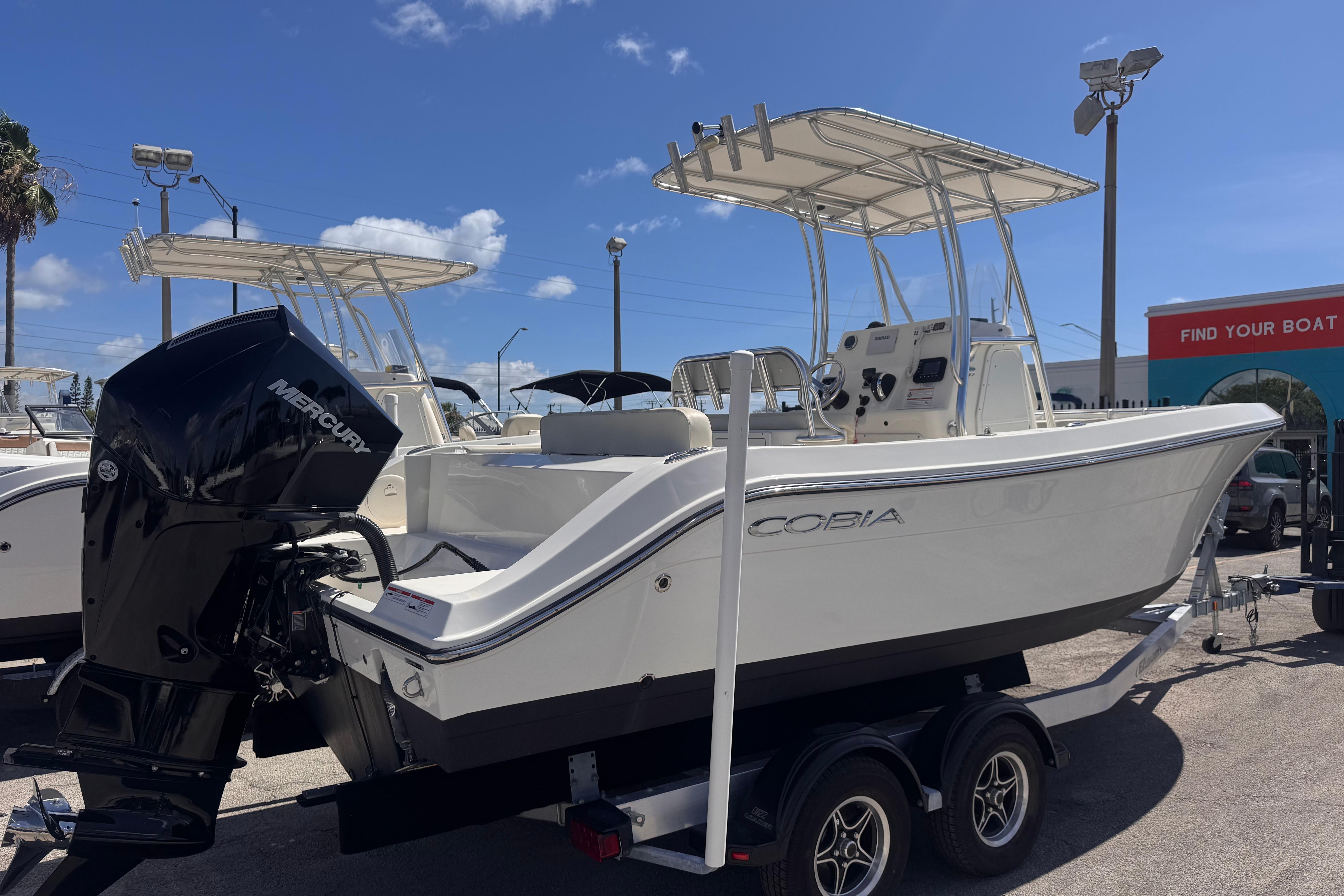 2023 Cobia 237 Center Console boat with Mercury engine on trailer under blue sky.