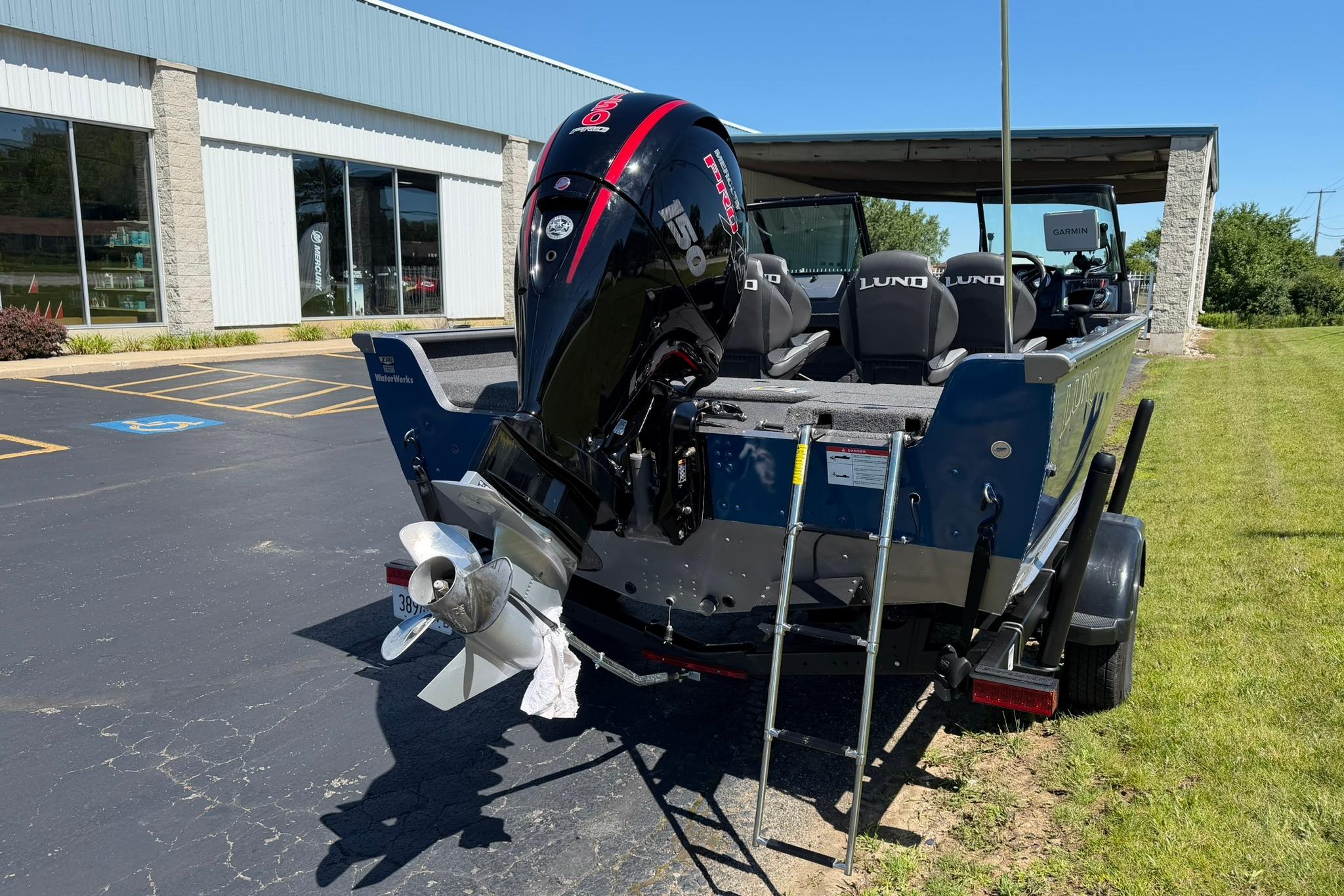 2024 Lund 1875 Impact XS Sport boat with powerful outboard motor, parked outdoors.