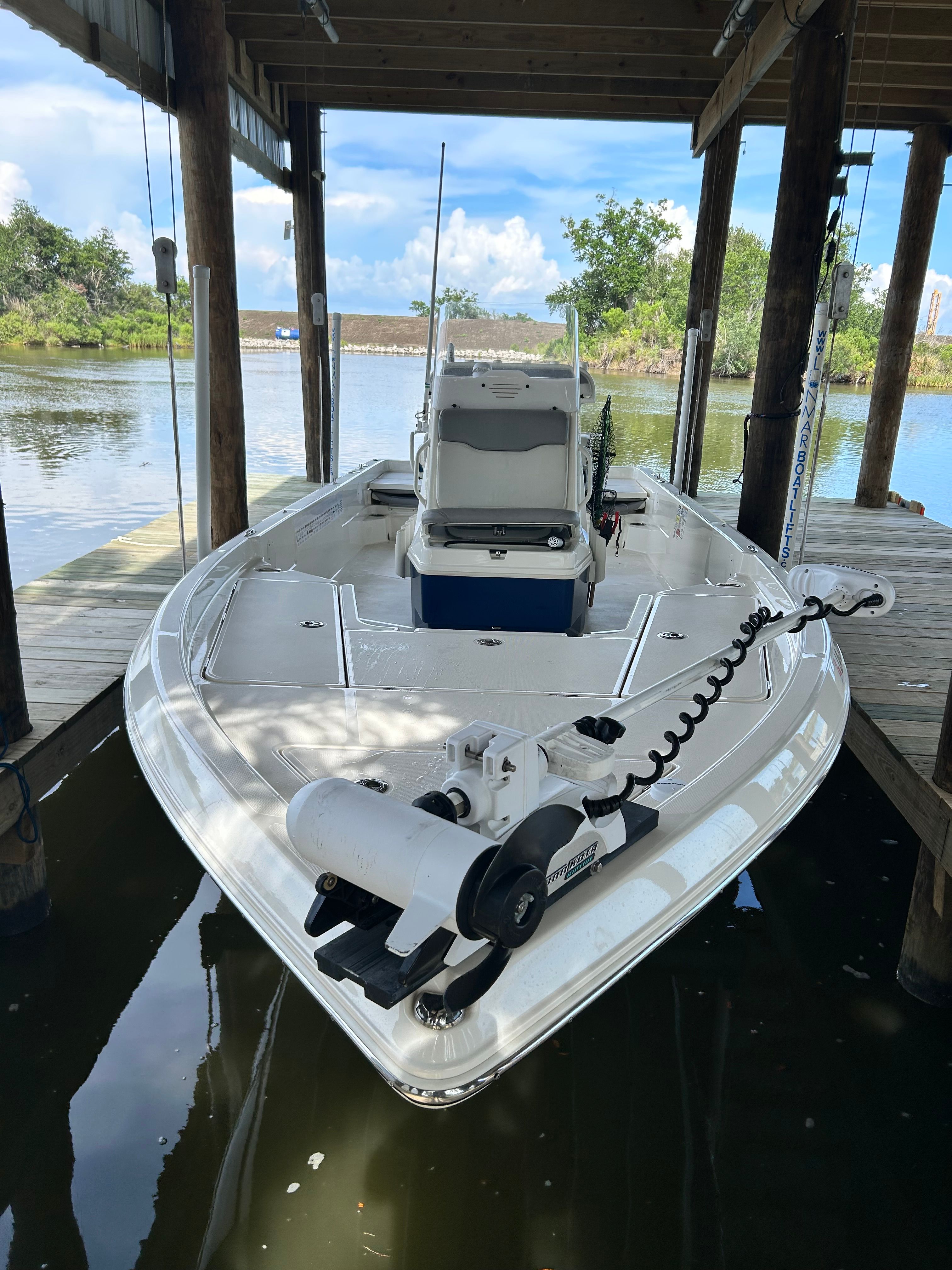 2016 Skeeter SX230 in a covered boathouse, surrounded by water and trees.