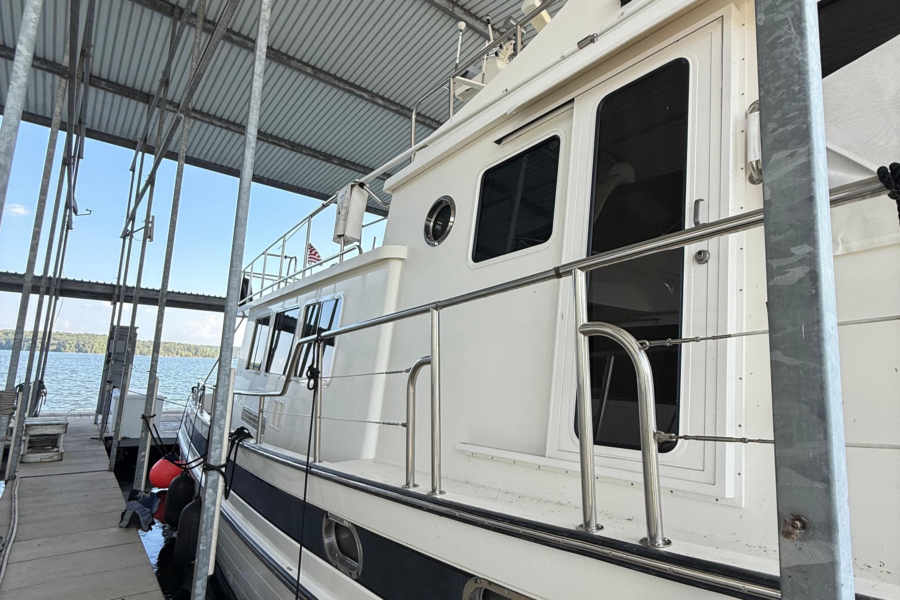 2007 Nordic Tug 54 docked under a covered marina with scenic water view.