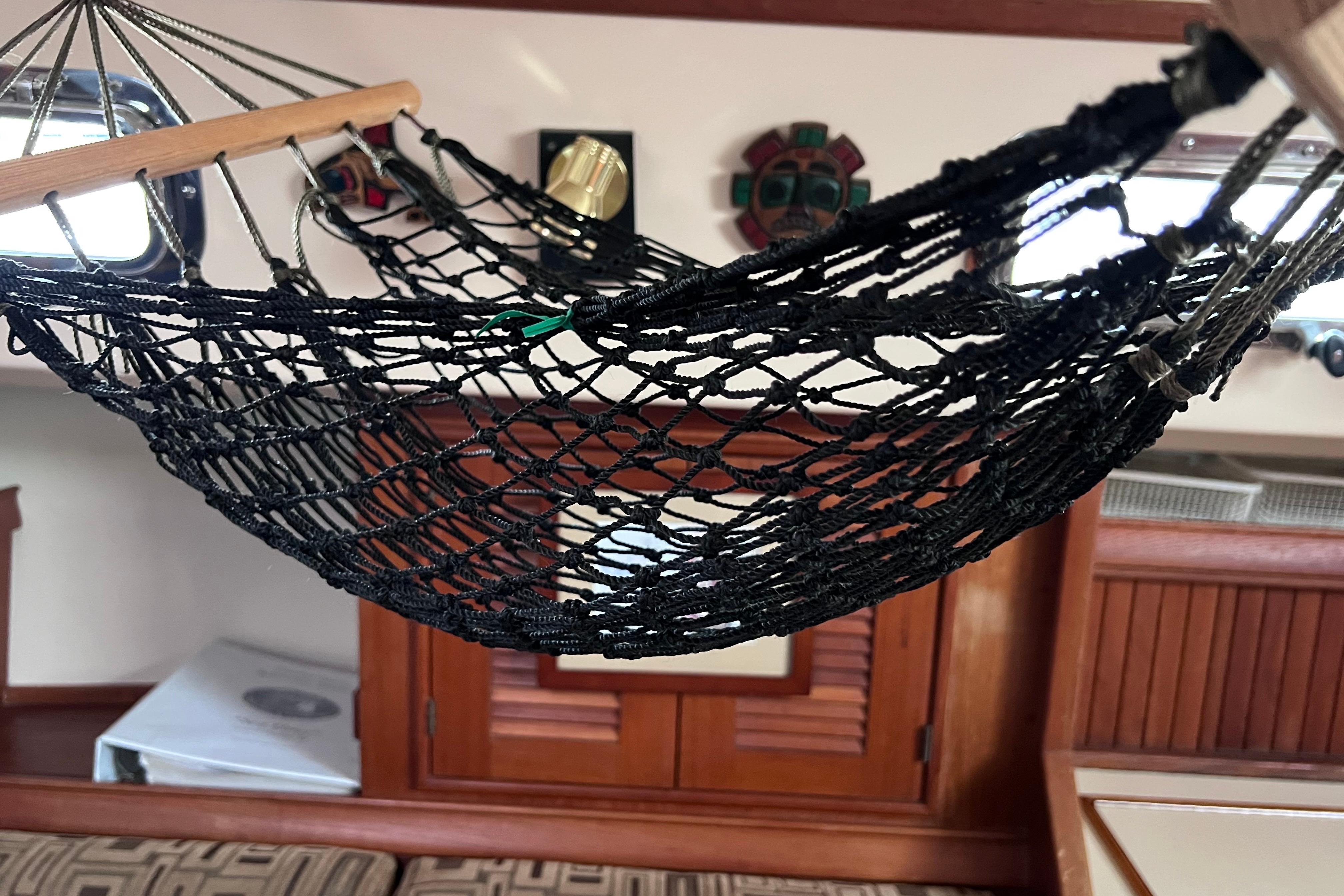 Black net hammock inside 1997 Island Packet 37 sailboat cabin, with wooden interior accents.