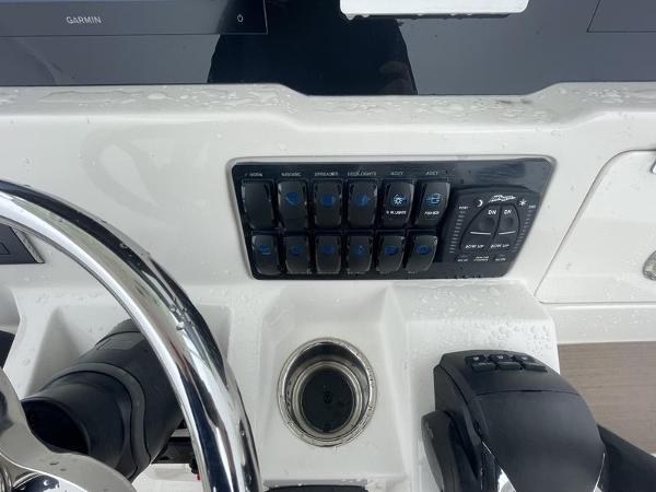 Control panel of 2023 Sailfish 290 CC boat with steering wheel and switches.