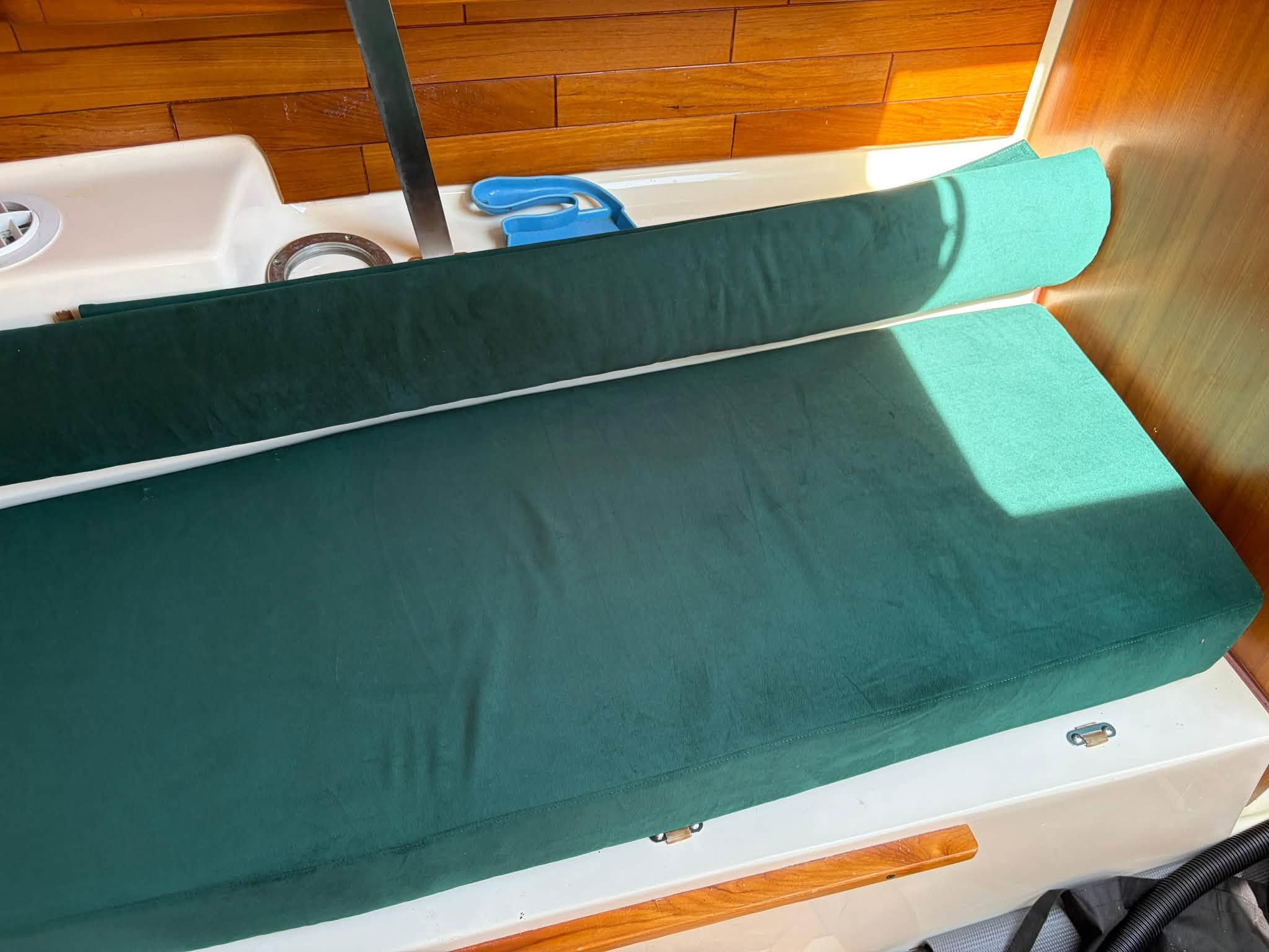 Green upholstery on a boat bench with wood paneling in the background.