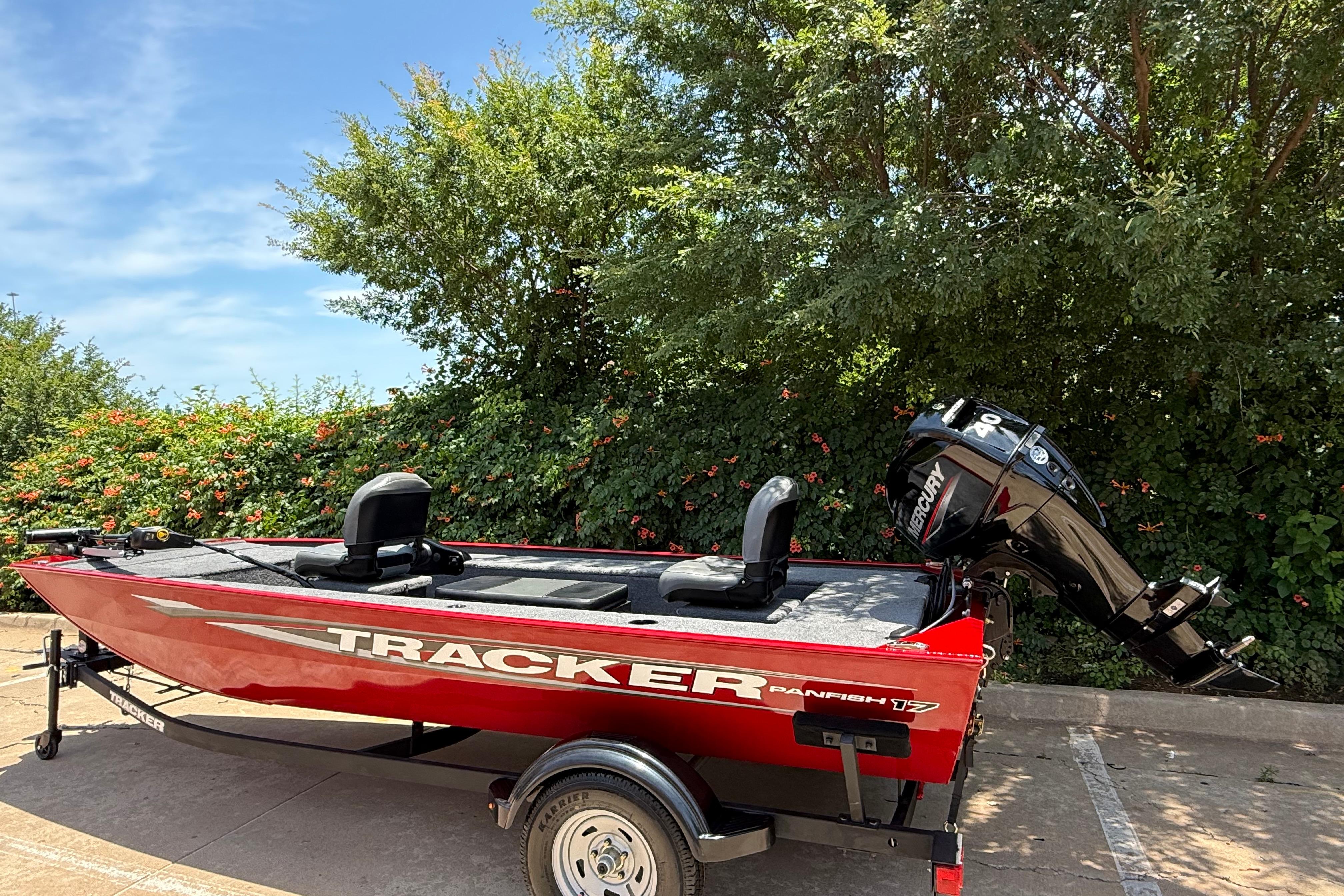 2025 Tracker Panfish 17 boat with Mercury engine, parked outdoors near greenery.