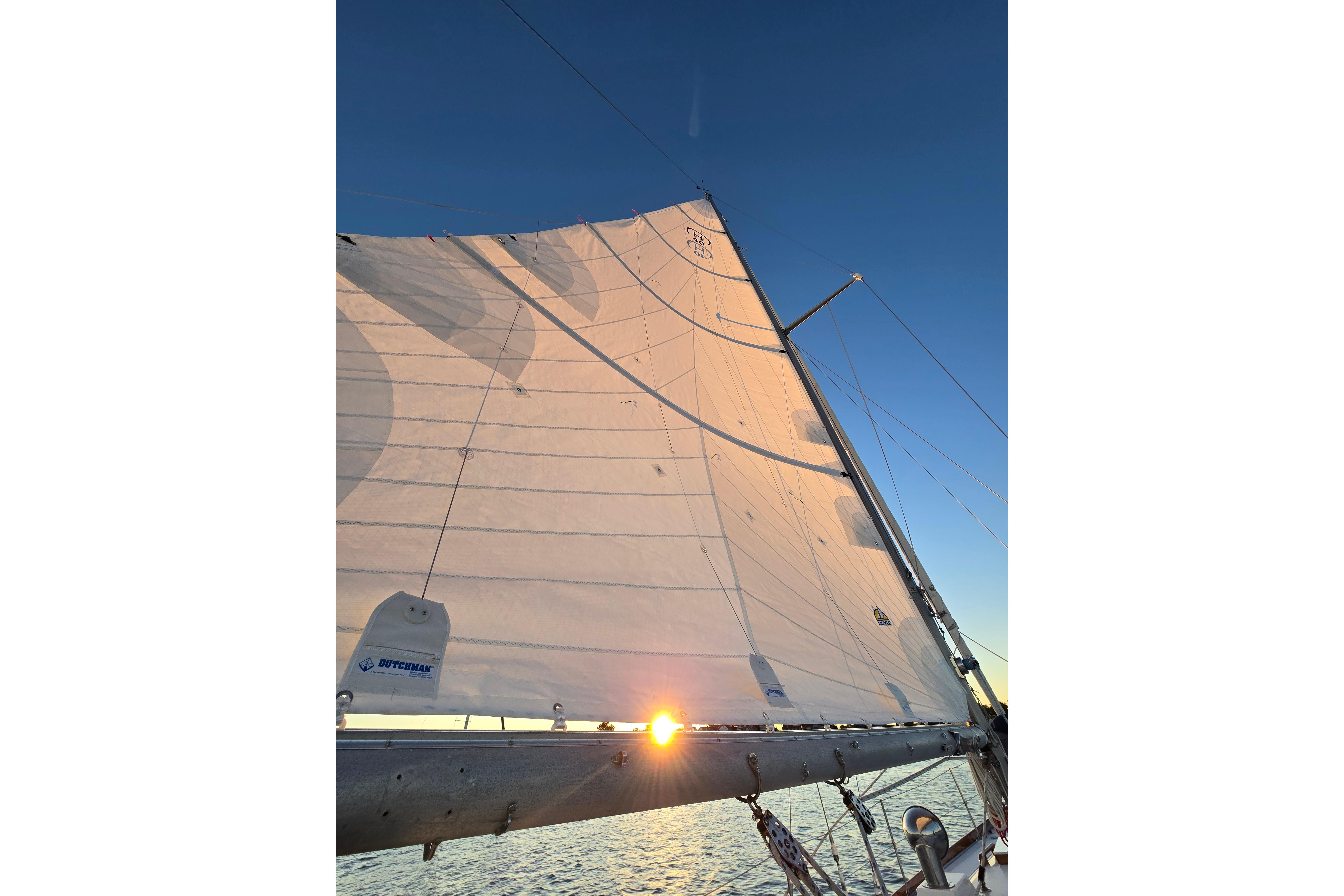 Sailing on a 1970 Hinckley Bermuda 40 with sunlit sails against a clear sky.