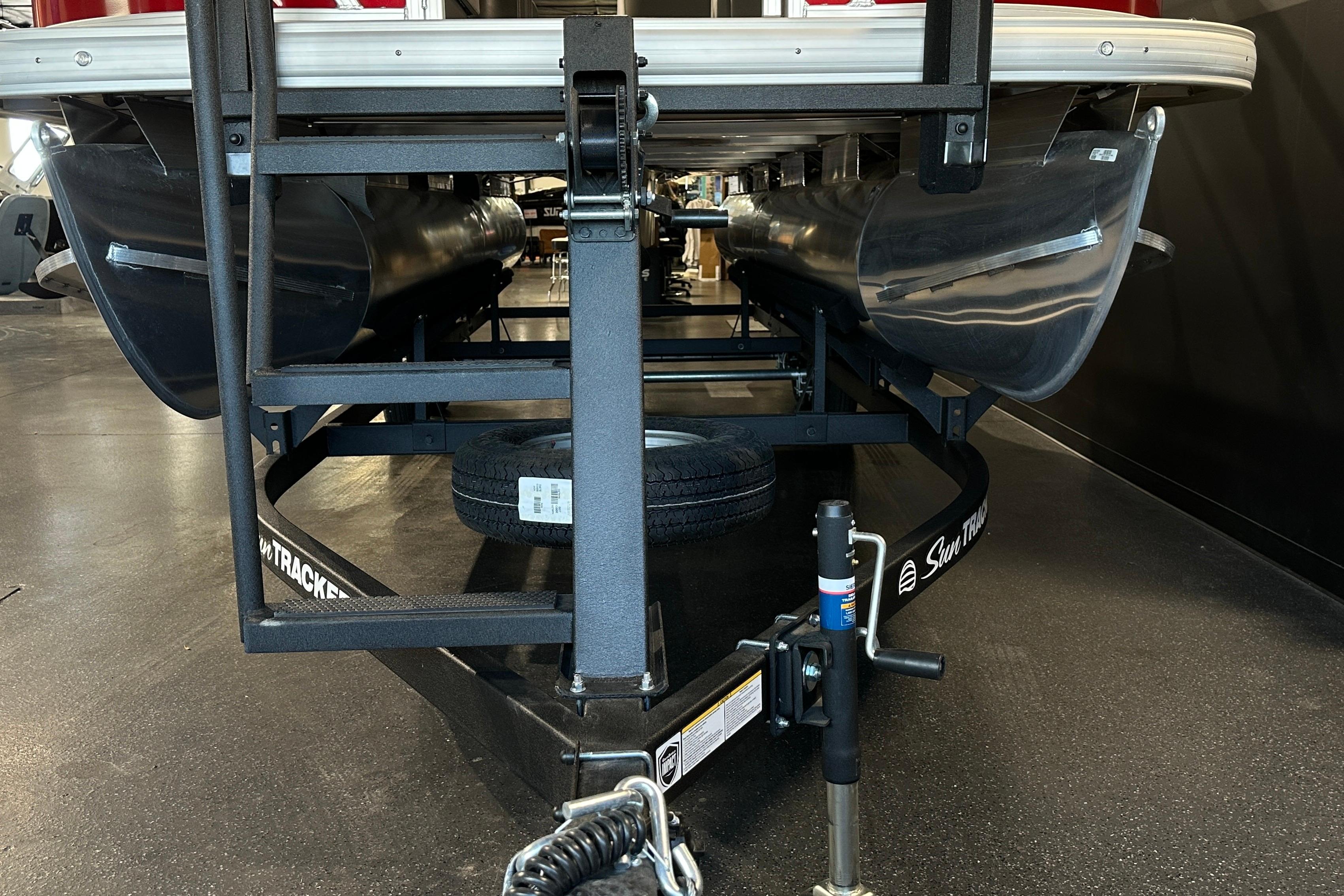 2026 Sun Tracker SportFish 22 DLX pontoon boat on trailer, indoor showroom view.
