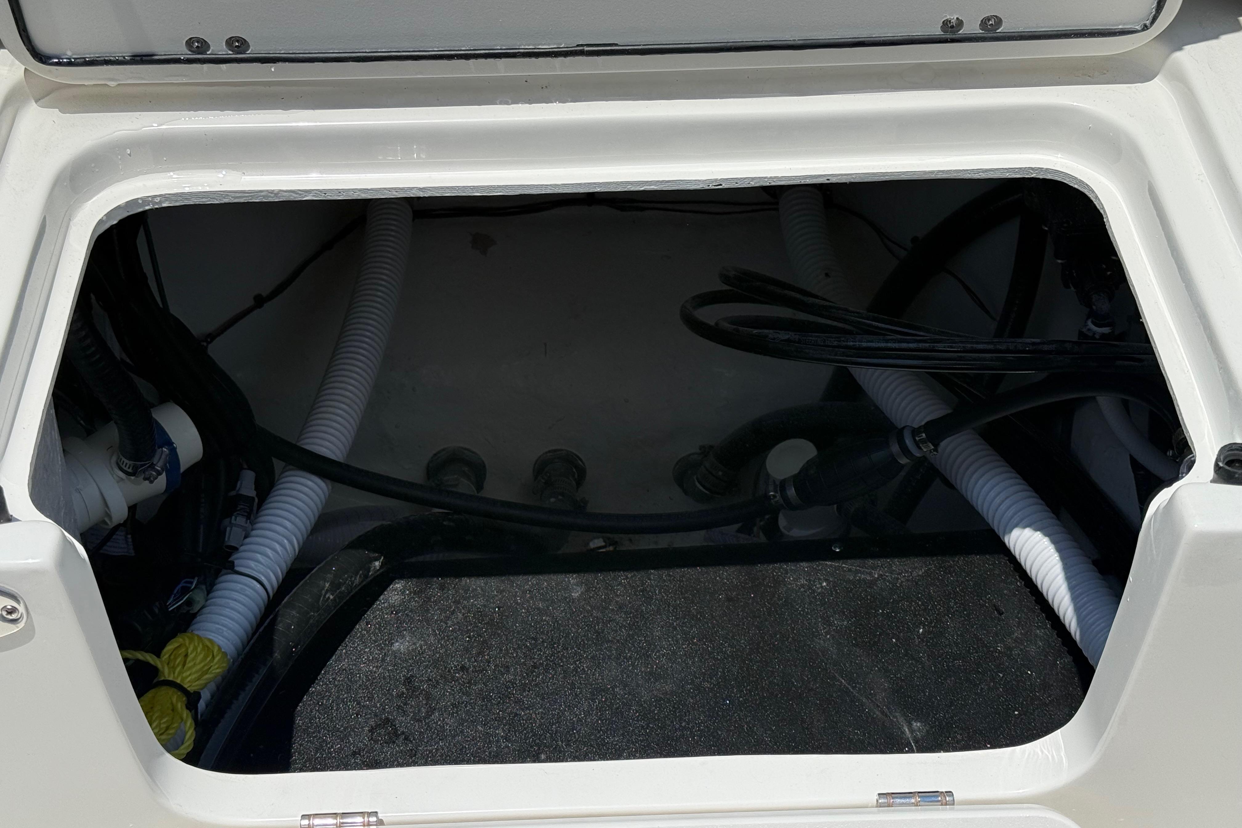 Open storage compartment of 2027 Key West 249 FS boat, showing internal wiring and hoses.