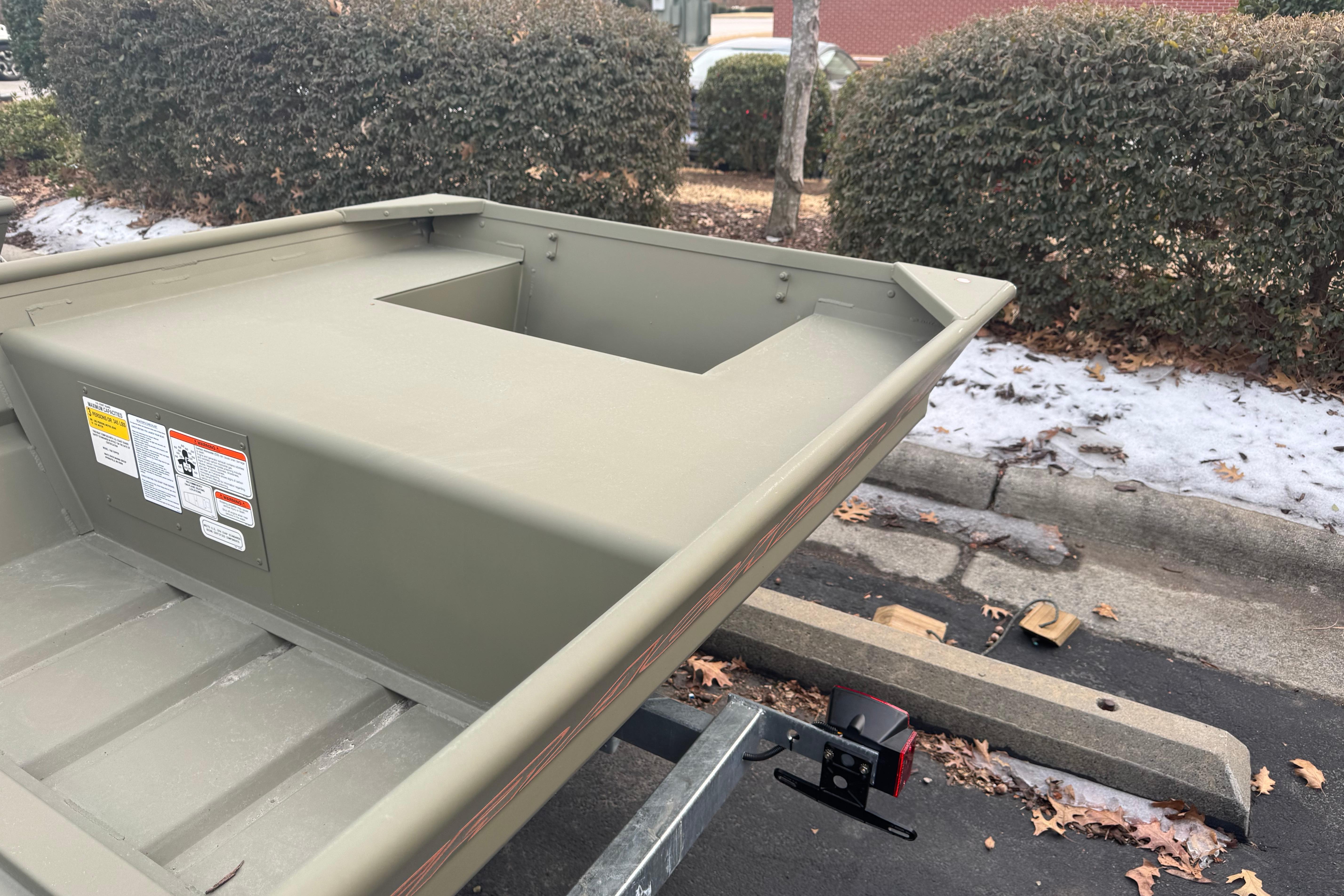 2026 Tracker Grizzly 14 Jon boat on trailer, parked near snowy curb.