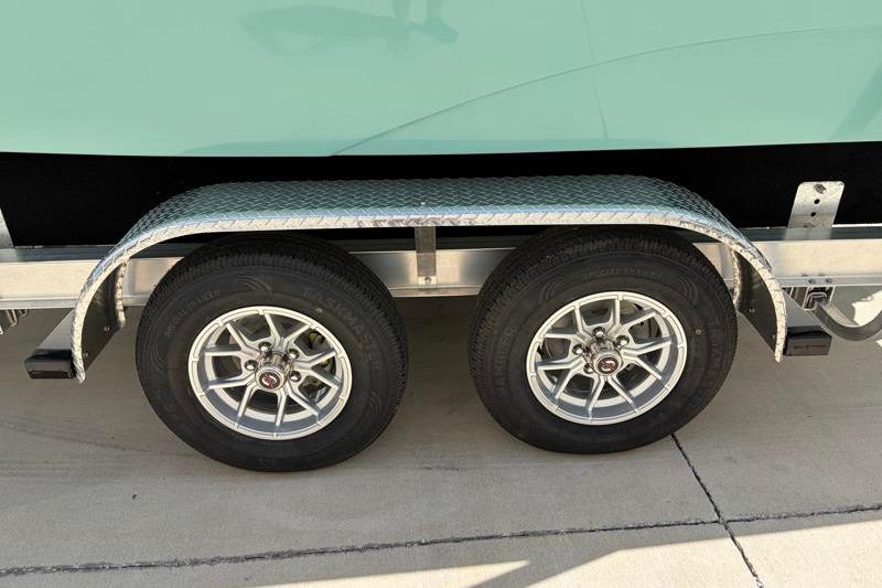 Trailer wheels of 2026 Hurricane SunDeck Sport 2050 OB boat on pavement.