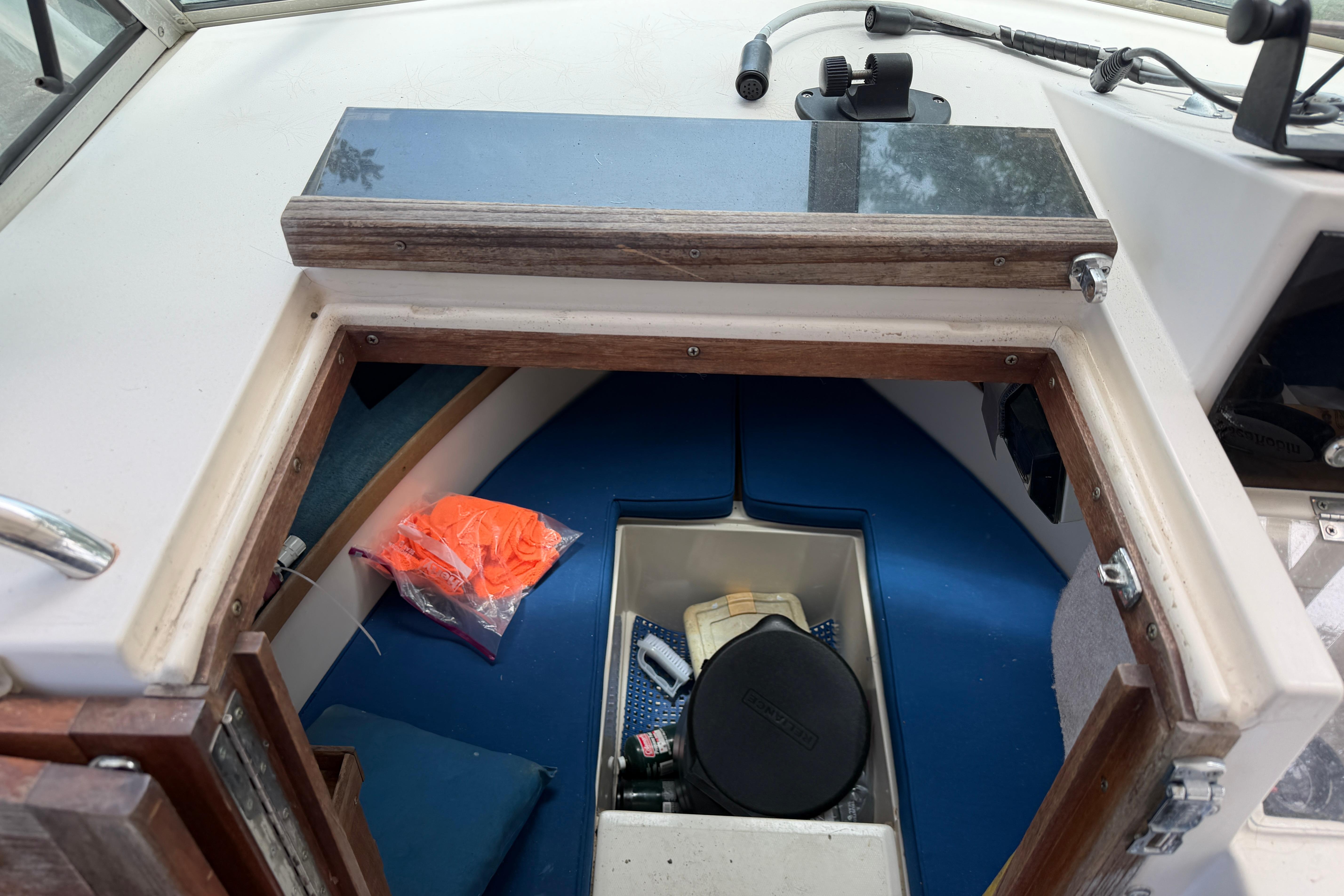 1987 Grady-White Seafarer 226 cabin interior with blue cushions and safety gear.