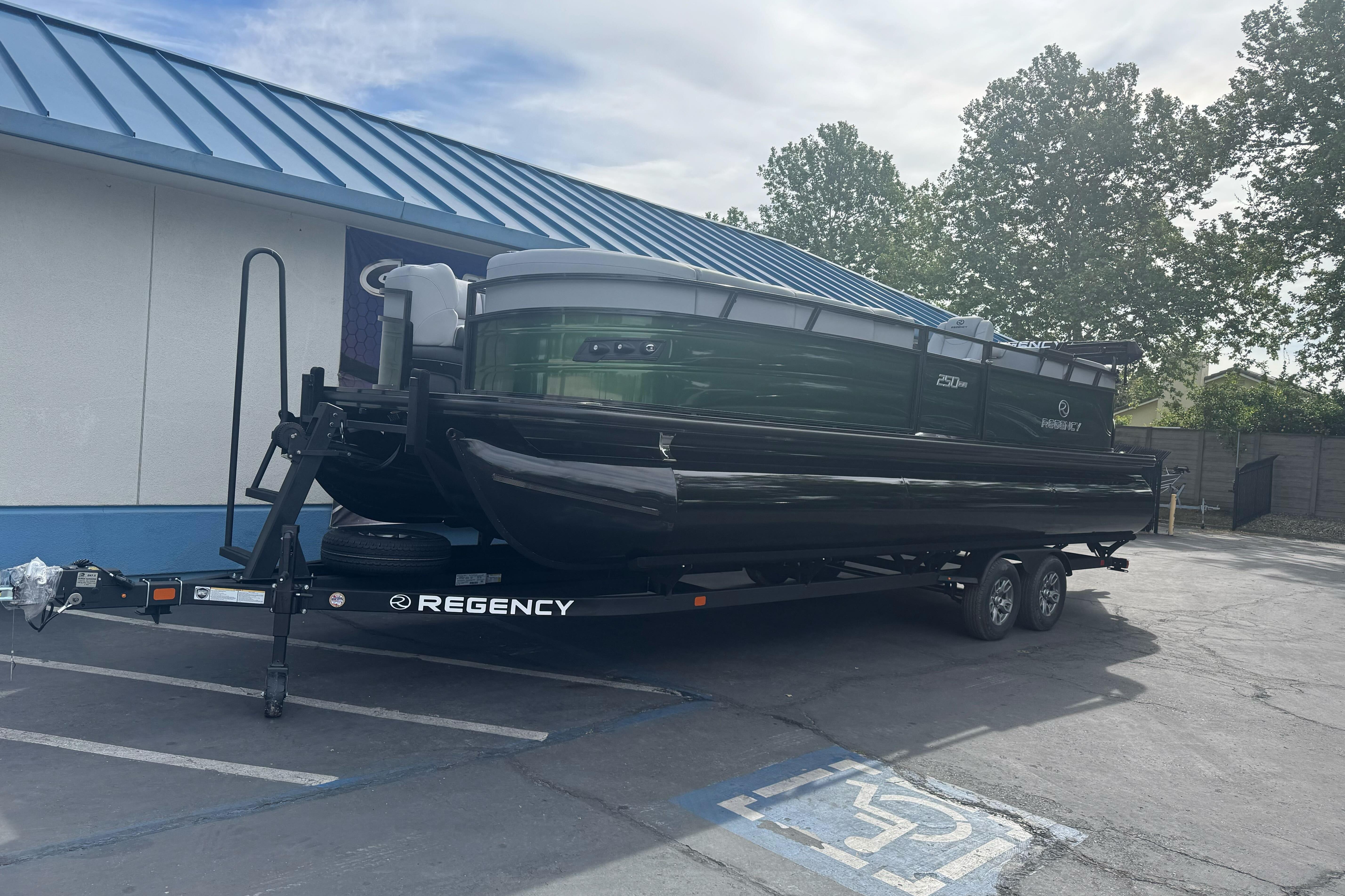 2026 Regency 250 DL pontoon boat on trailer, parked near a building.