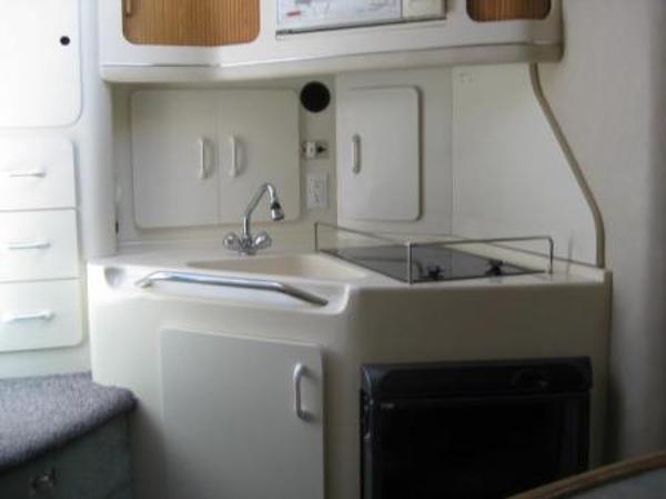 1996 Sea Ray 300 Sundancer boat kitchen with sink, stove, and storage cabinets.