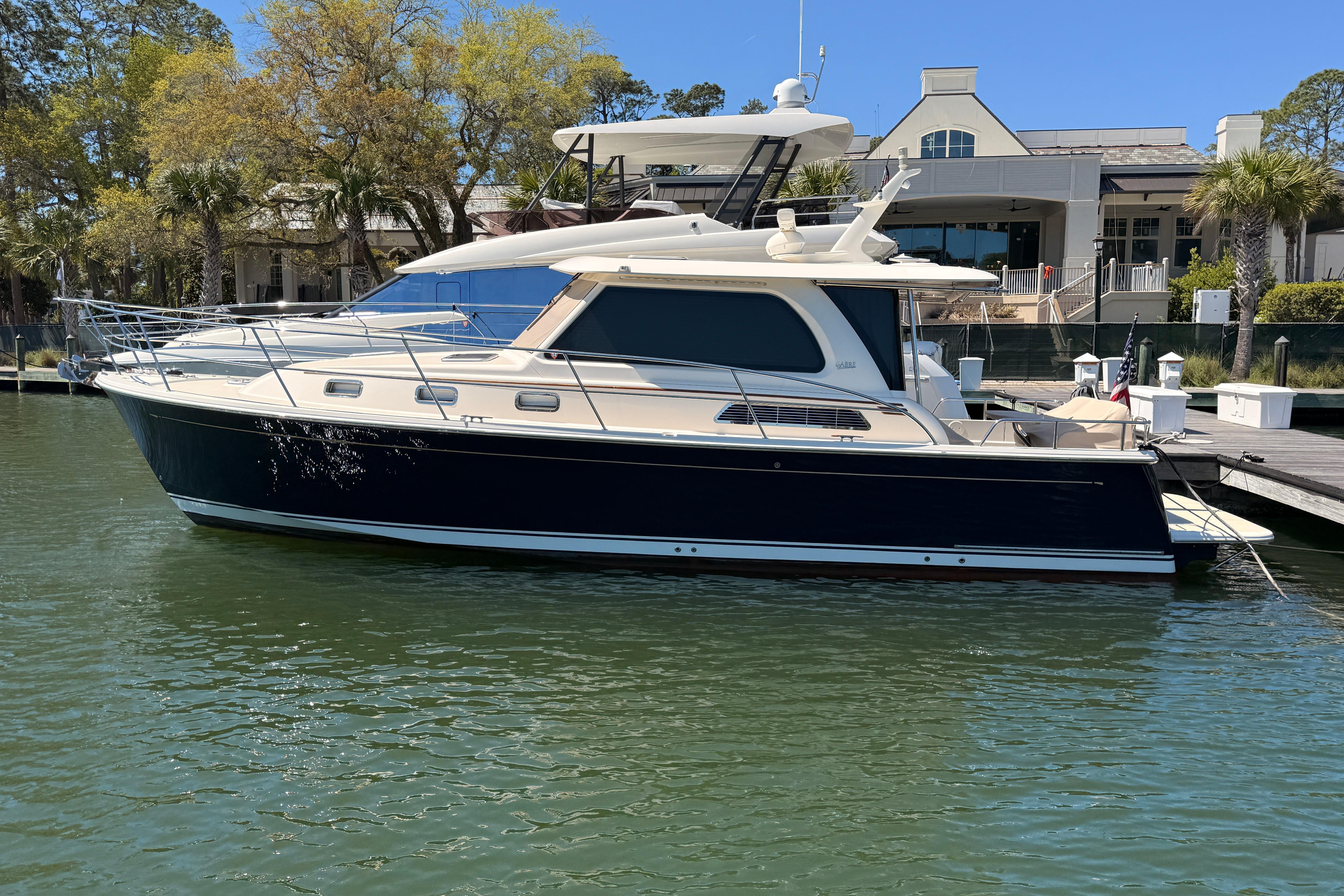 2022 Sabre 38 Salon Express yacht docked at marina, surrounded by trees and buildings.