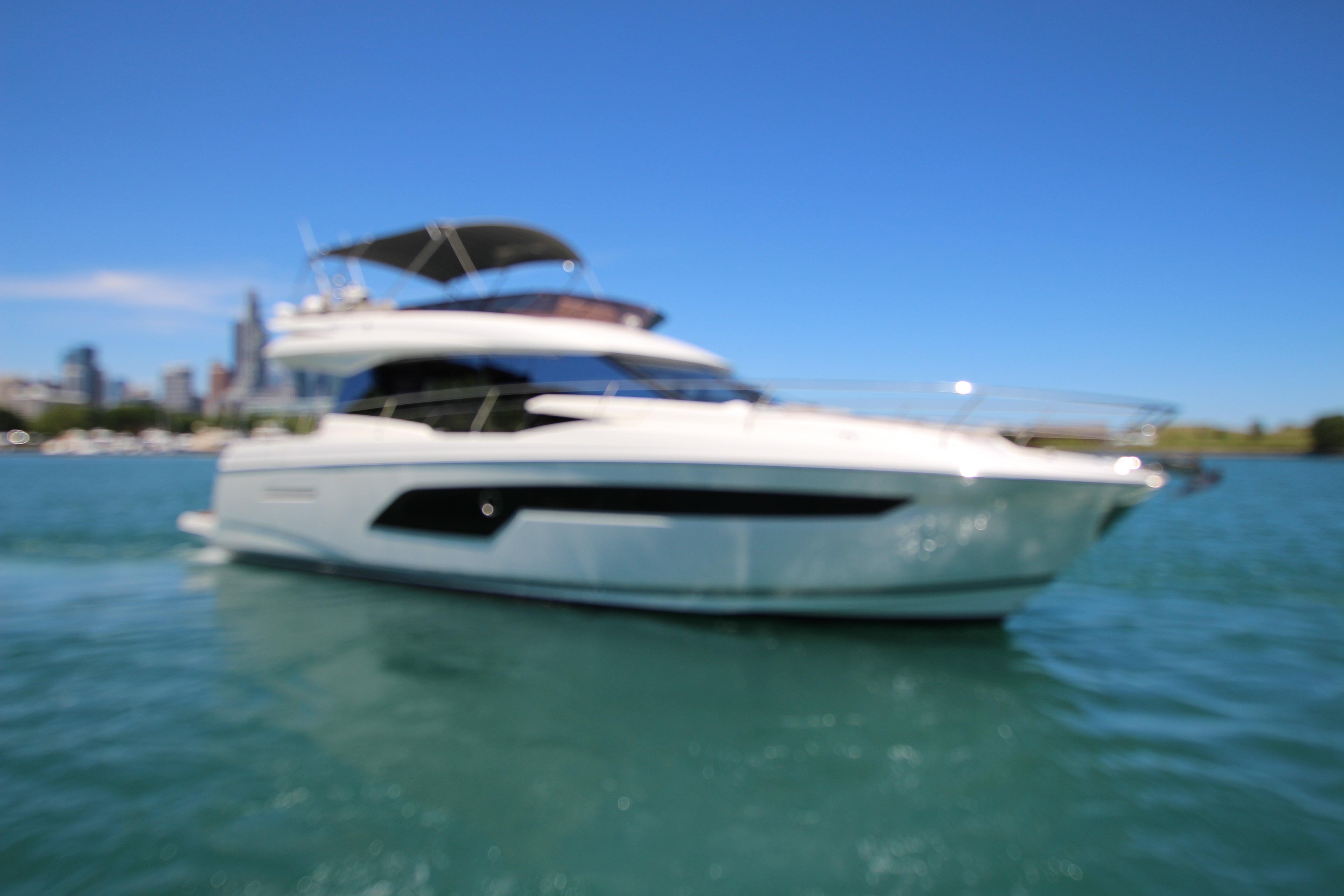 Blurry image of a 2022 Prestige 520 yacht on blue water under clear sky.