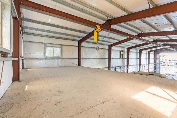 Spacious interior of 1985 Custom Larson Boathouse with metal beams and large windows.