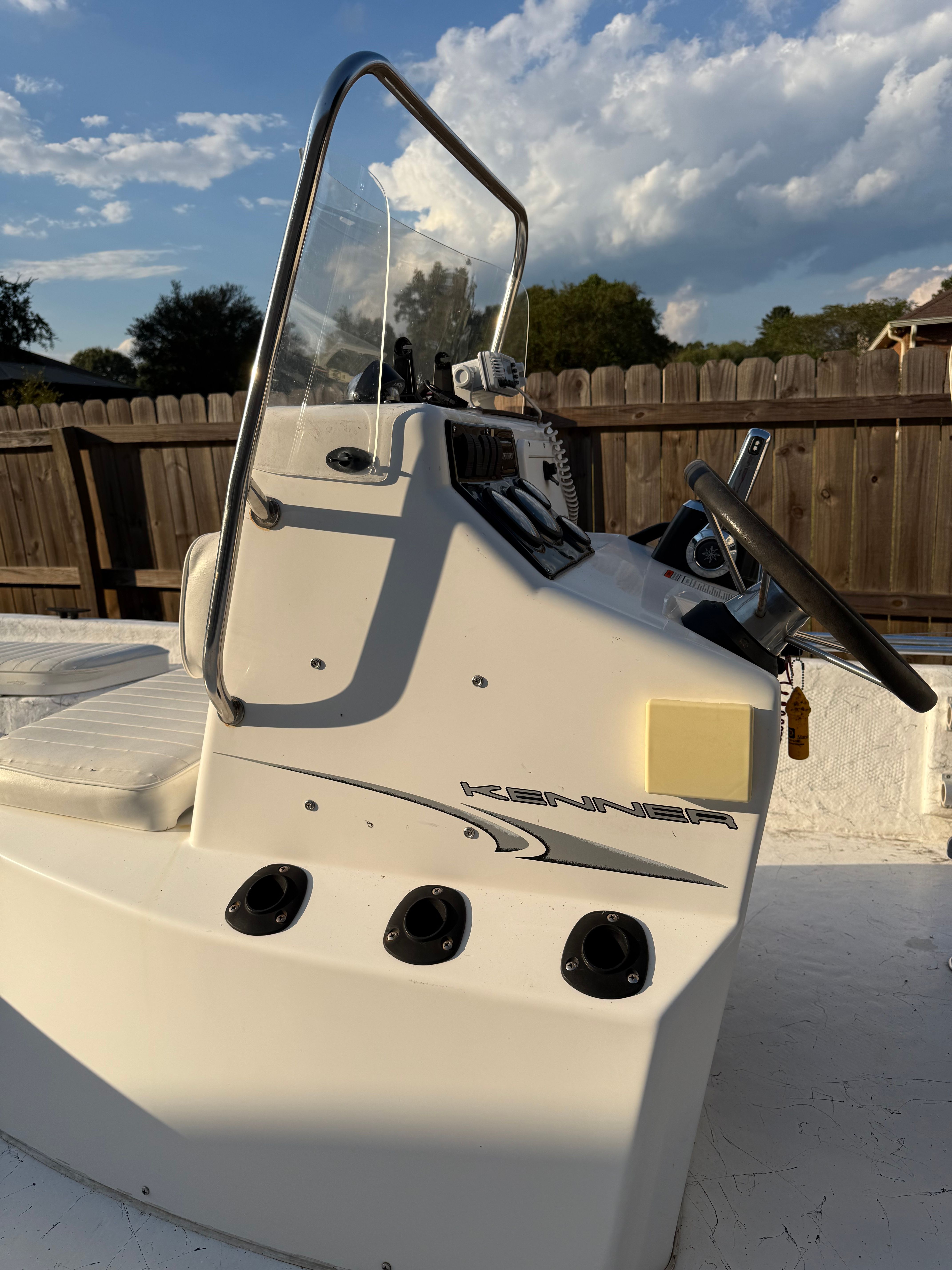 A Kenner boat with a console and steering wheel, surrounded by a wooden fence.